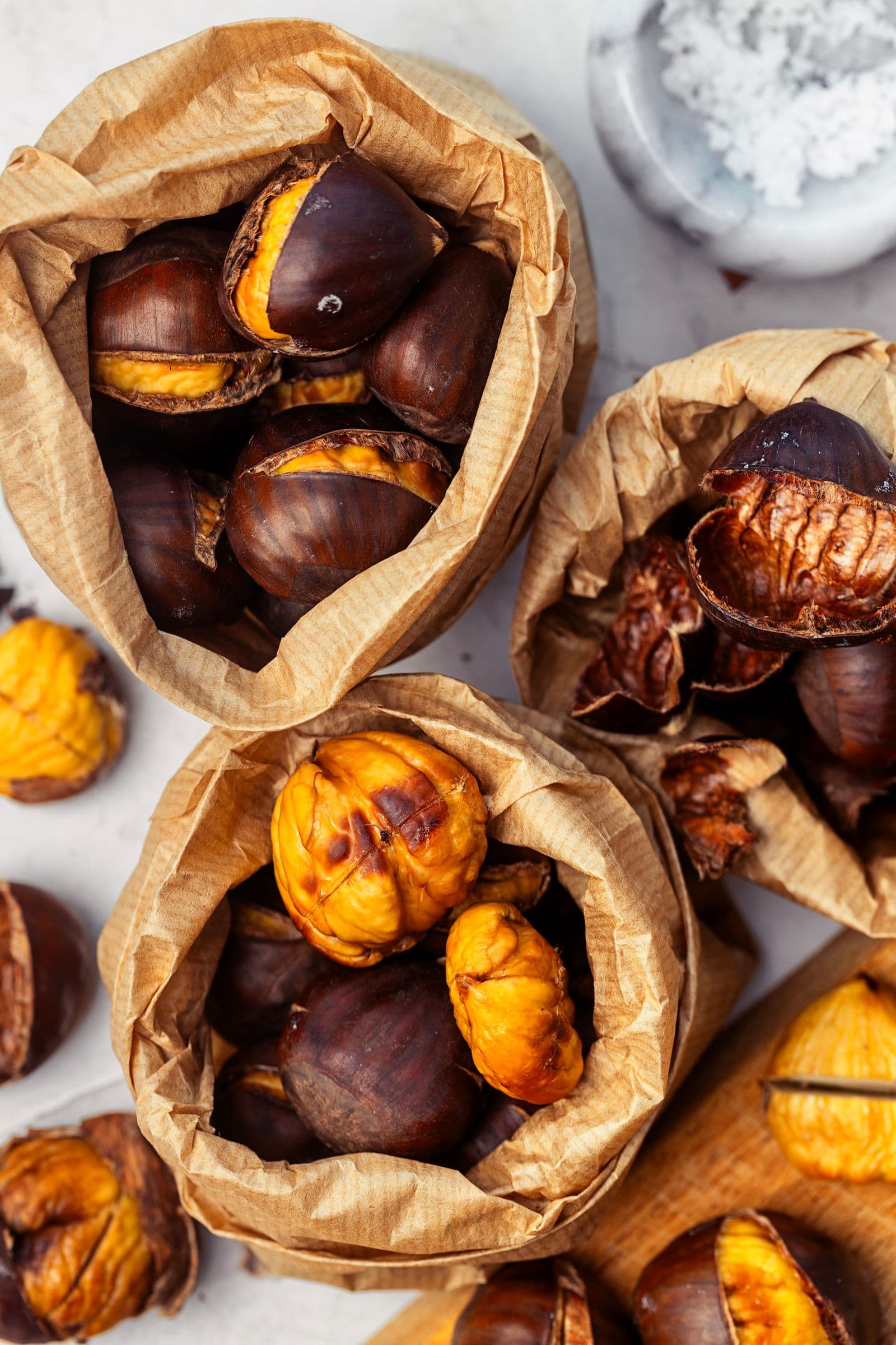 “Close-up view of the paper bags filled with roasted chestnuts, some already peeled and golden.”