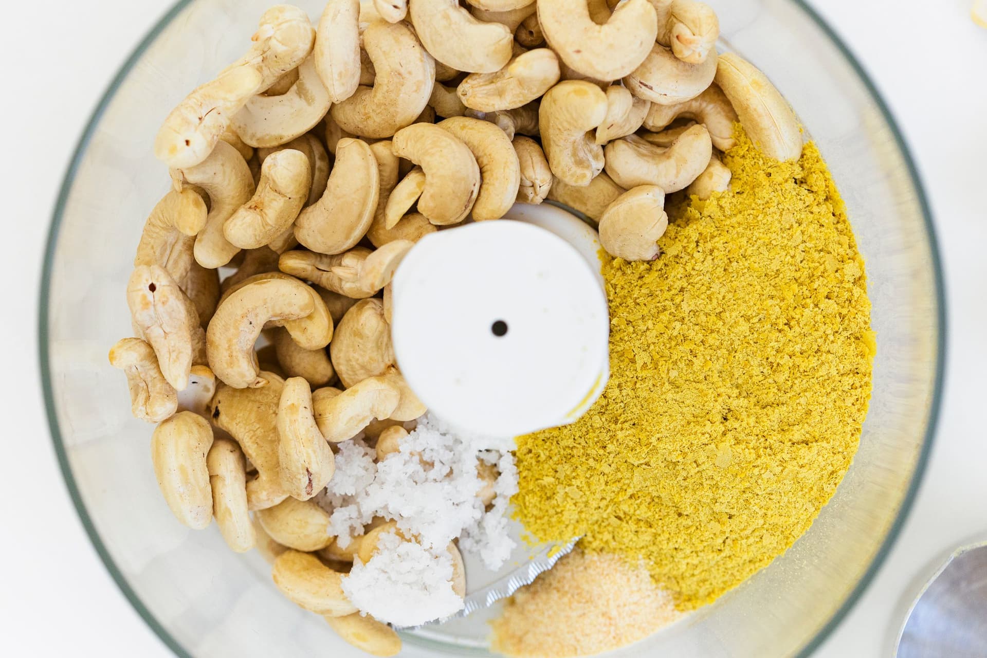 Cashews, nutritional yeast, garlic powder and salt inside a food processor.