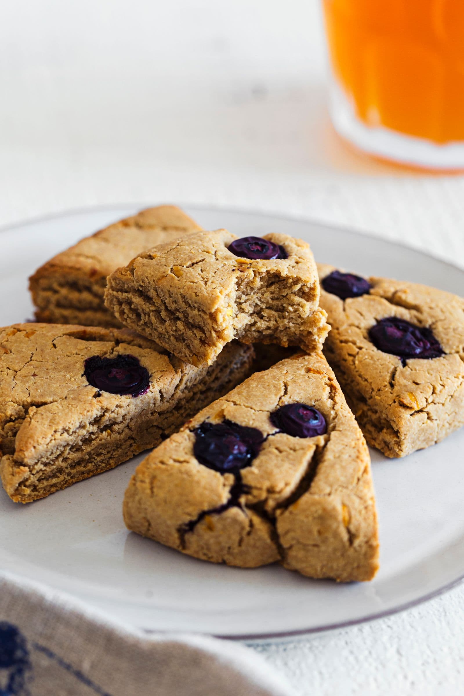 Close-up of golden-brown vegan scones with bursting blueberries on top.