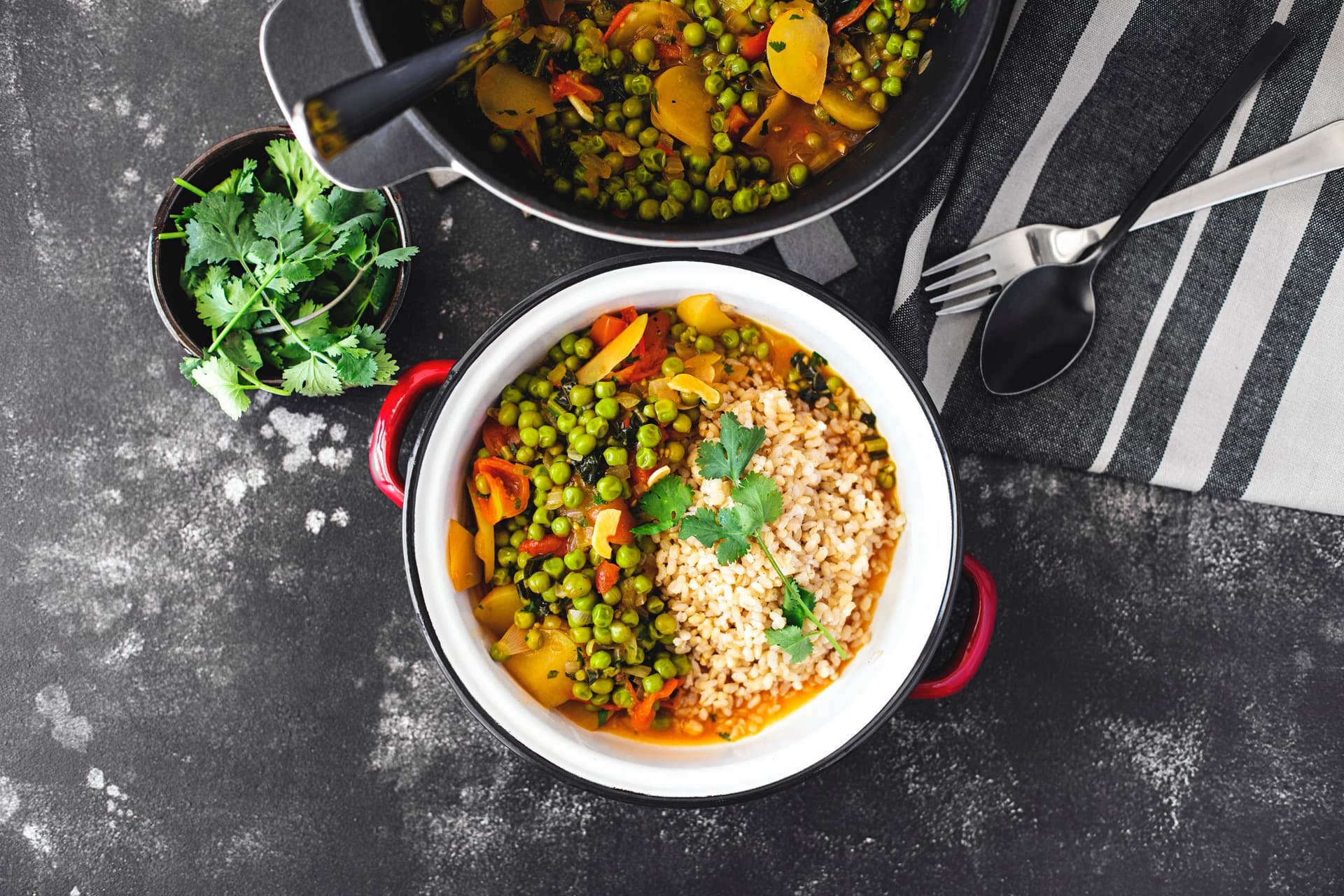 Bowl of Portuguese-style vegan pea stew with potatoes, cherry tomatoes, and rice, garnished with fresh coriander.