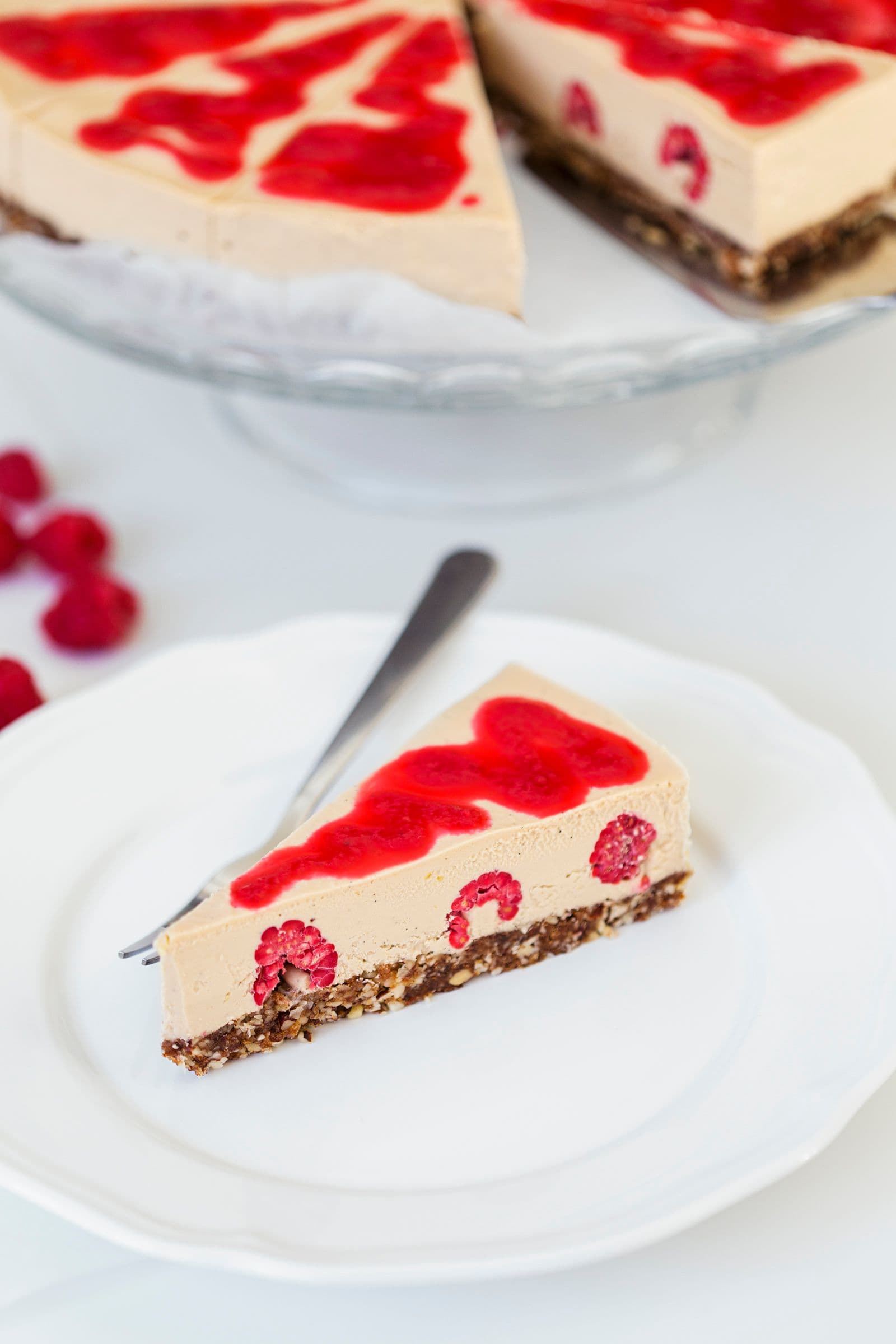 Cheesecake inteiro numa base e uma fatia servida num prato branco pequeno.