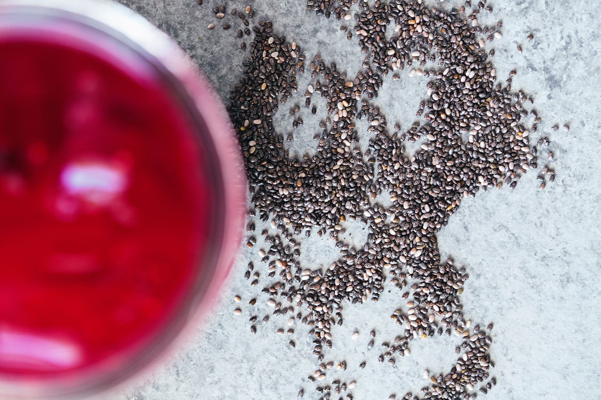 Overhead of blackberry juice next to scattered chia seeds.