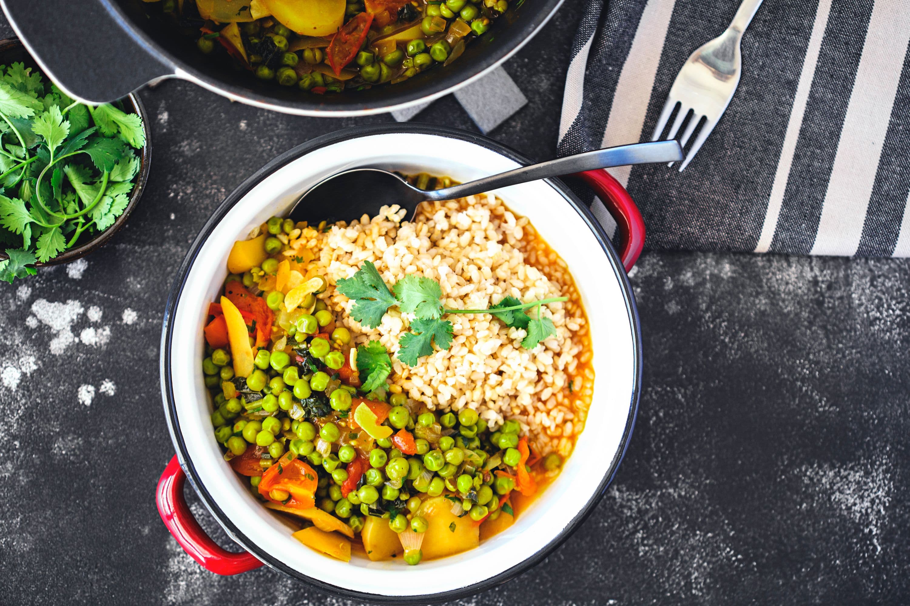 White bowl filled with rice and pea stew, garnished with fresh coriander leaves.