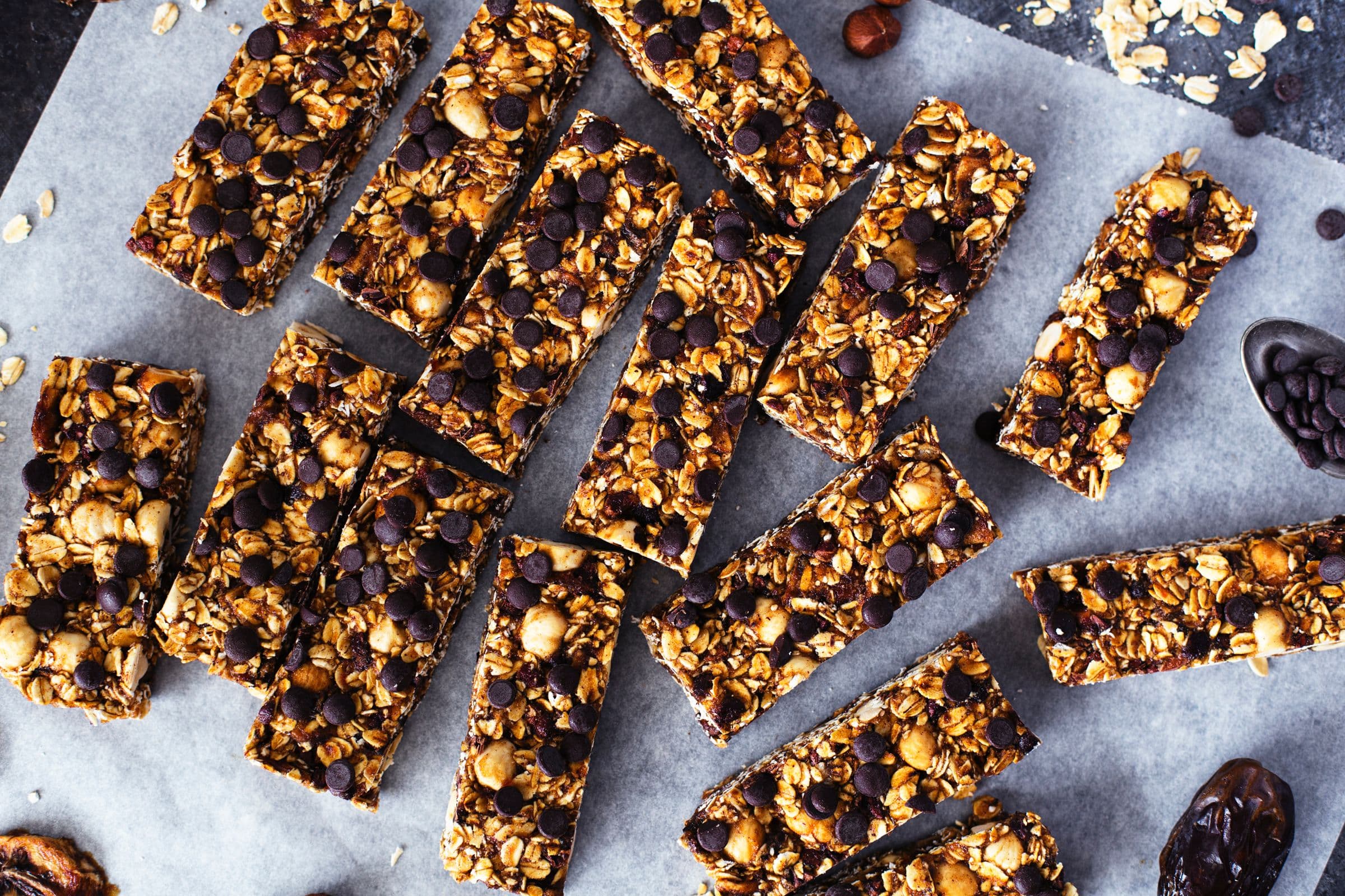 Multiple granola bars laid out on parchment in an irregular pattern.