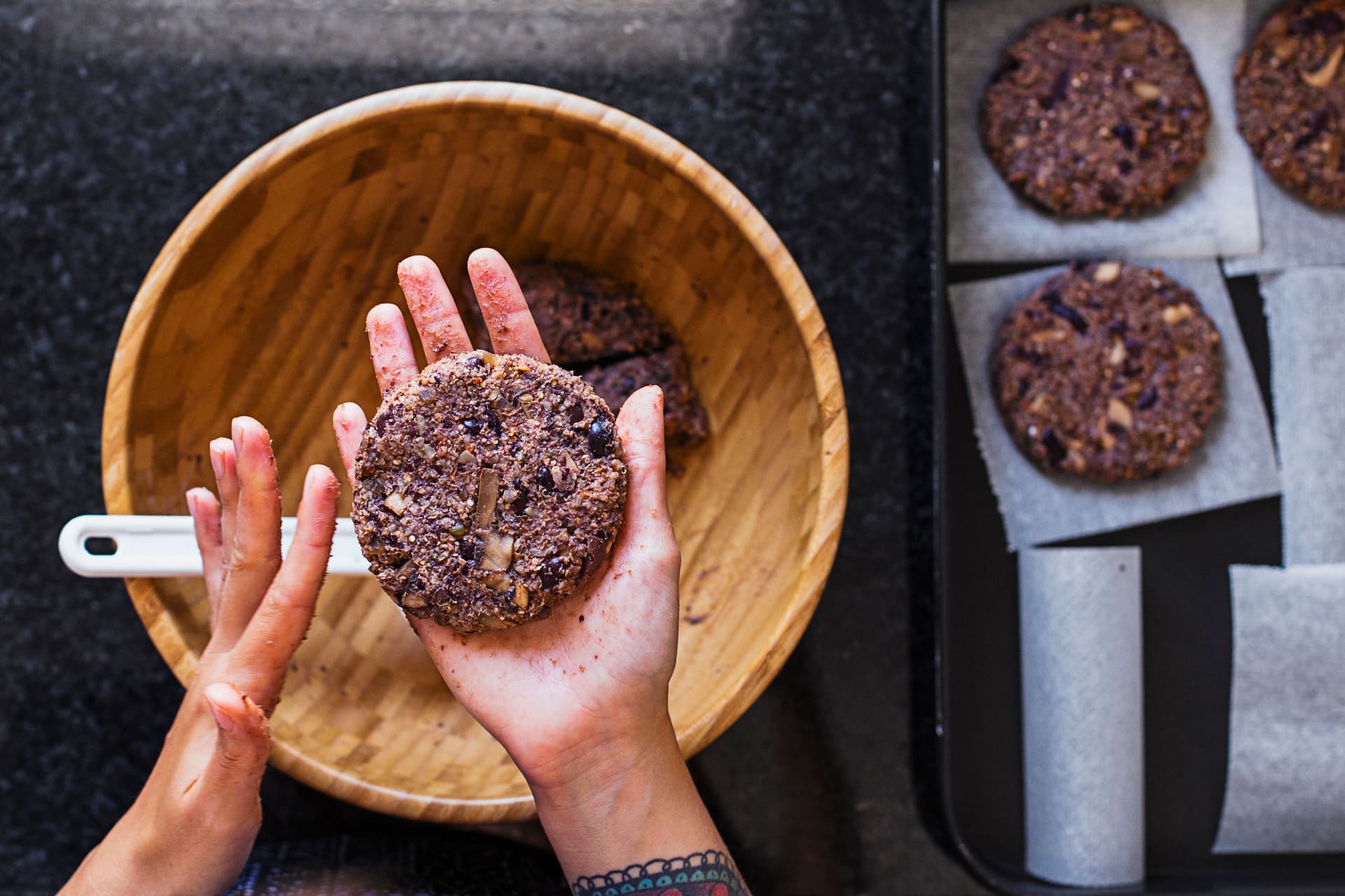 Hands shaping a black bean burger patty over a mixing bowl.