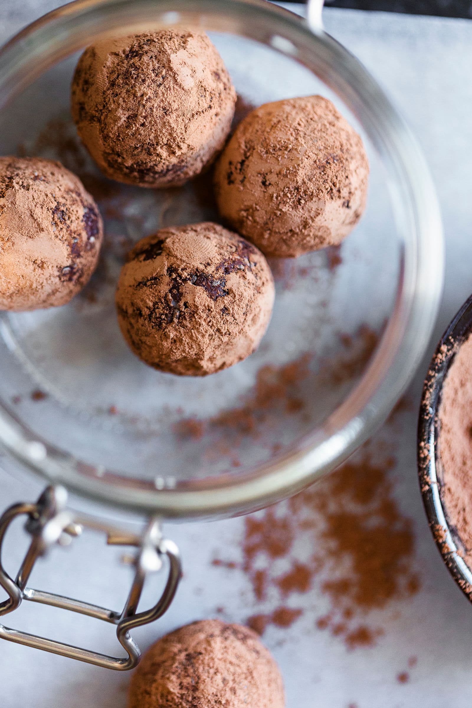 Glass jar with cacao almond energy balls and cocoa powder.