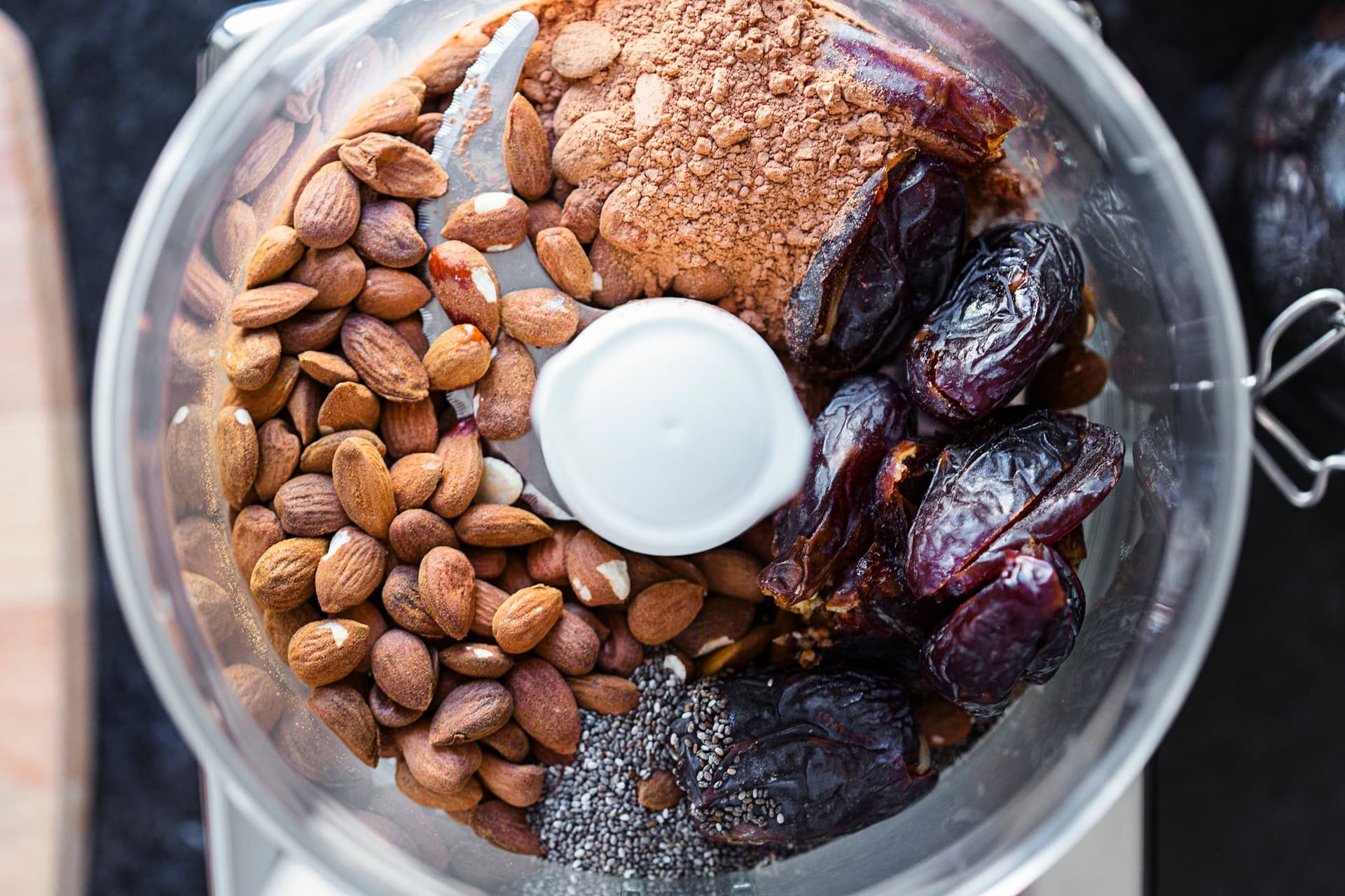 Processador de alimentos com amêndoas, tâmaras, cacau cru e sementes de chia.