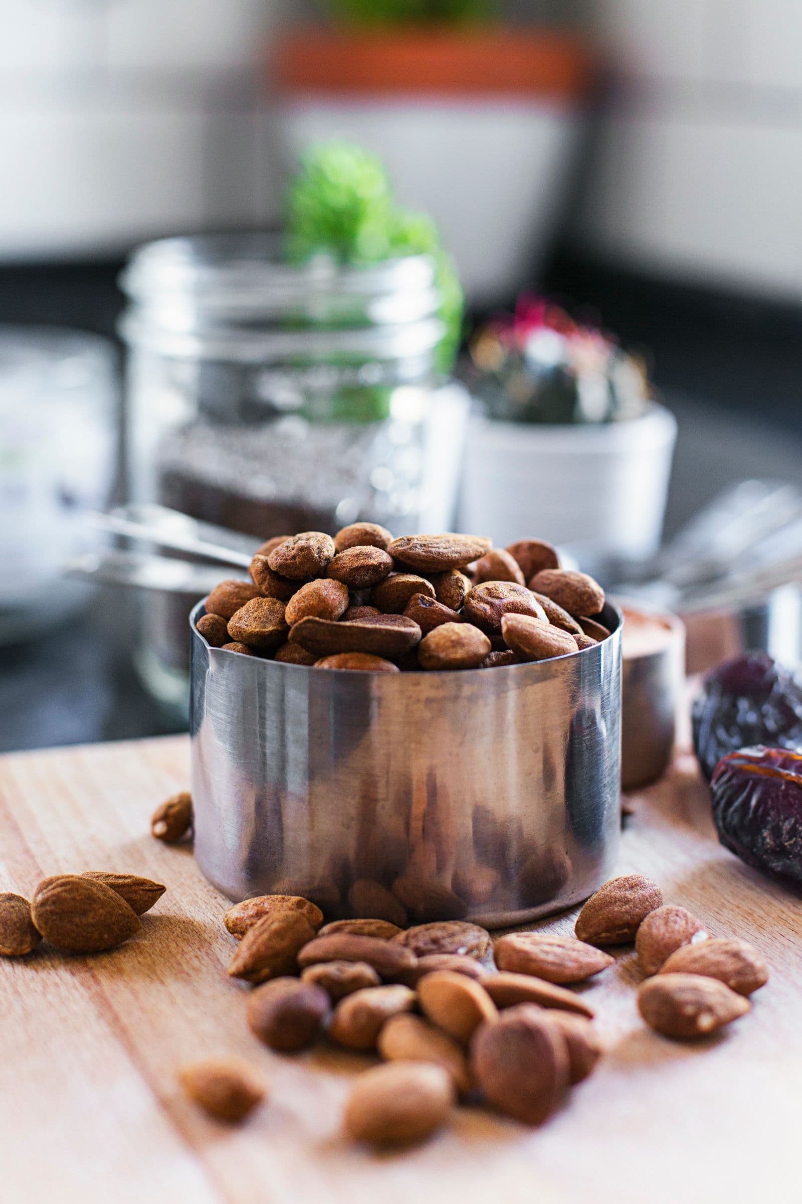 Measuring cup filled with almonds on a wooden board.