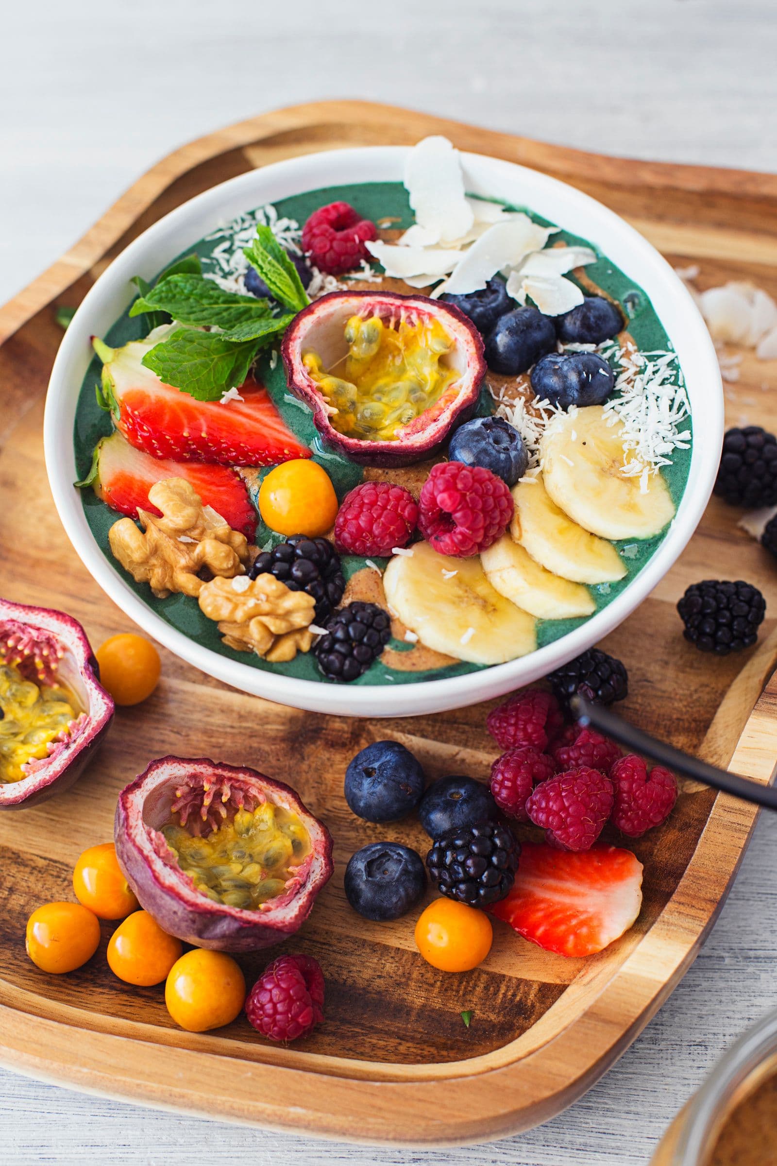 Taça de smoothie vibrante com frutos vermelhos, maracujá, banana, coco e hortelã fresca.