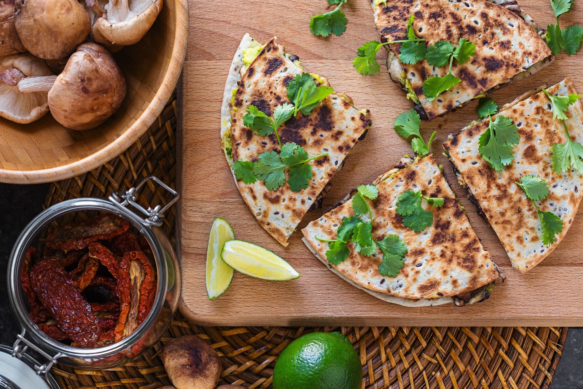 Triângulos de quesadilla vegan com guacamole e coentros frescos numa tábua de madeira.