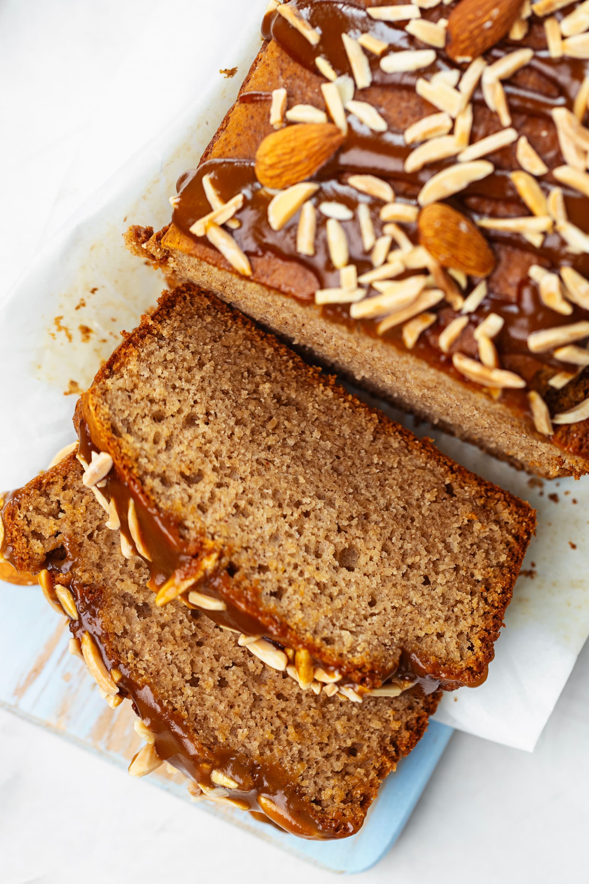Sliced almond cake from above, revealing a soft tender crumb with coconut caramel and slivered almonds on top.
