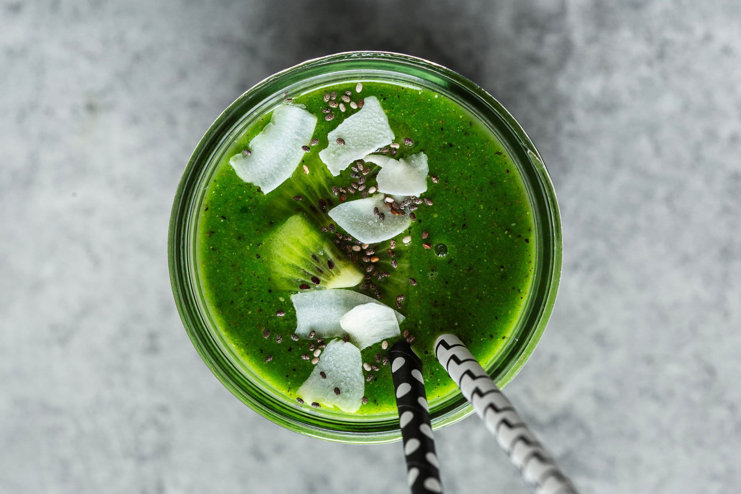 Smoothie verde vibrante servido em frasco de vidro com kiwi, coco e sementes de chia