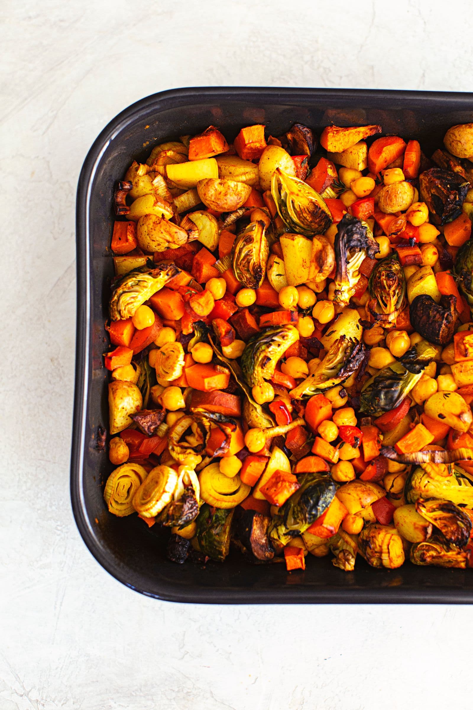 Roasted vegetables and chickpeas in a baking dish, base for vegan savoury crumble.