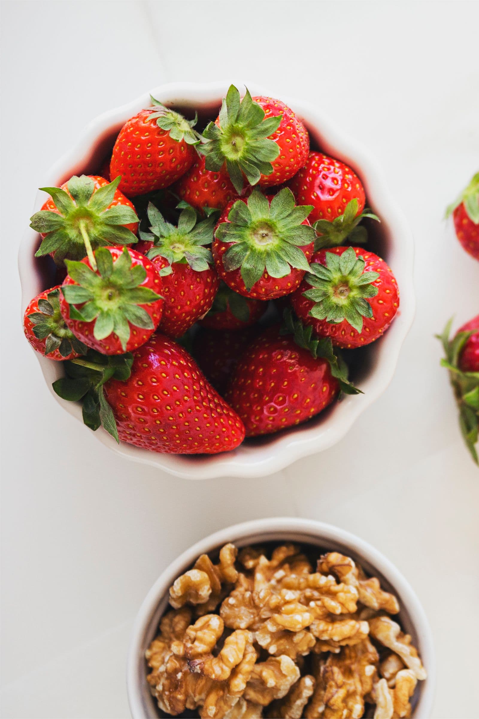 Fresh strawberries in a white bowl, ready to use as topping for the cheesecake.