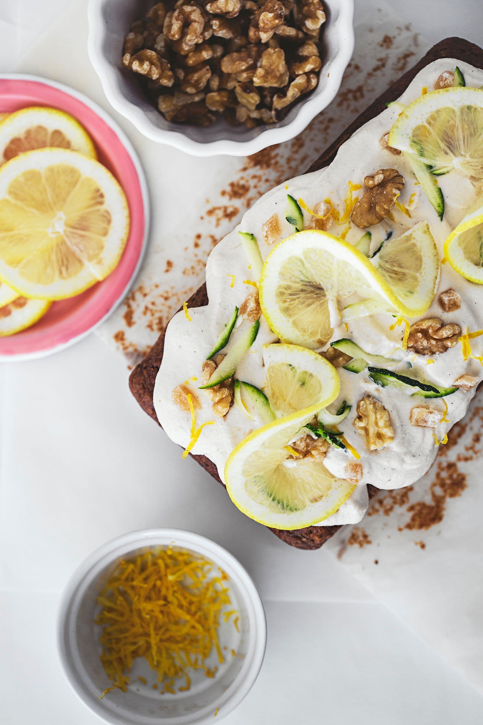 Finished zucchini and lemon cake topped with frosting and citrus garnish.