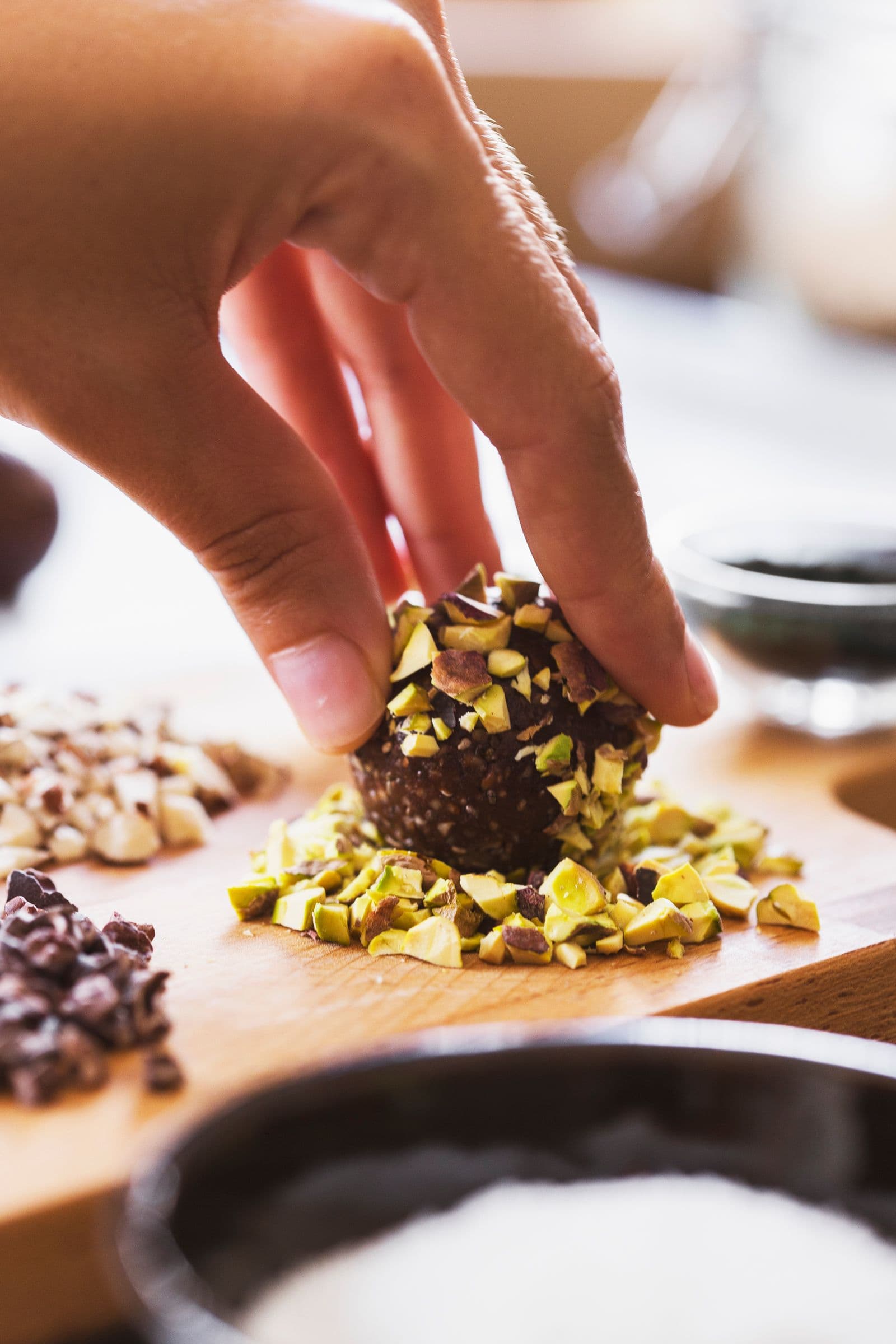 Hand rolling an energy ball in chopped pistachios.