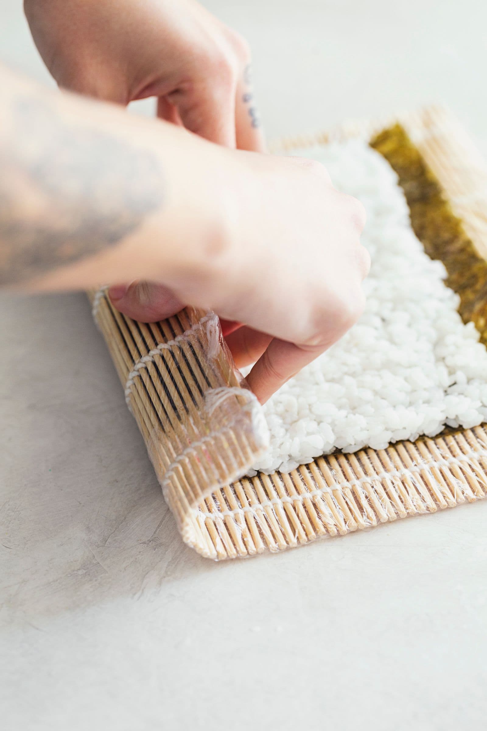 Hands carefully rolling sushi roll.