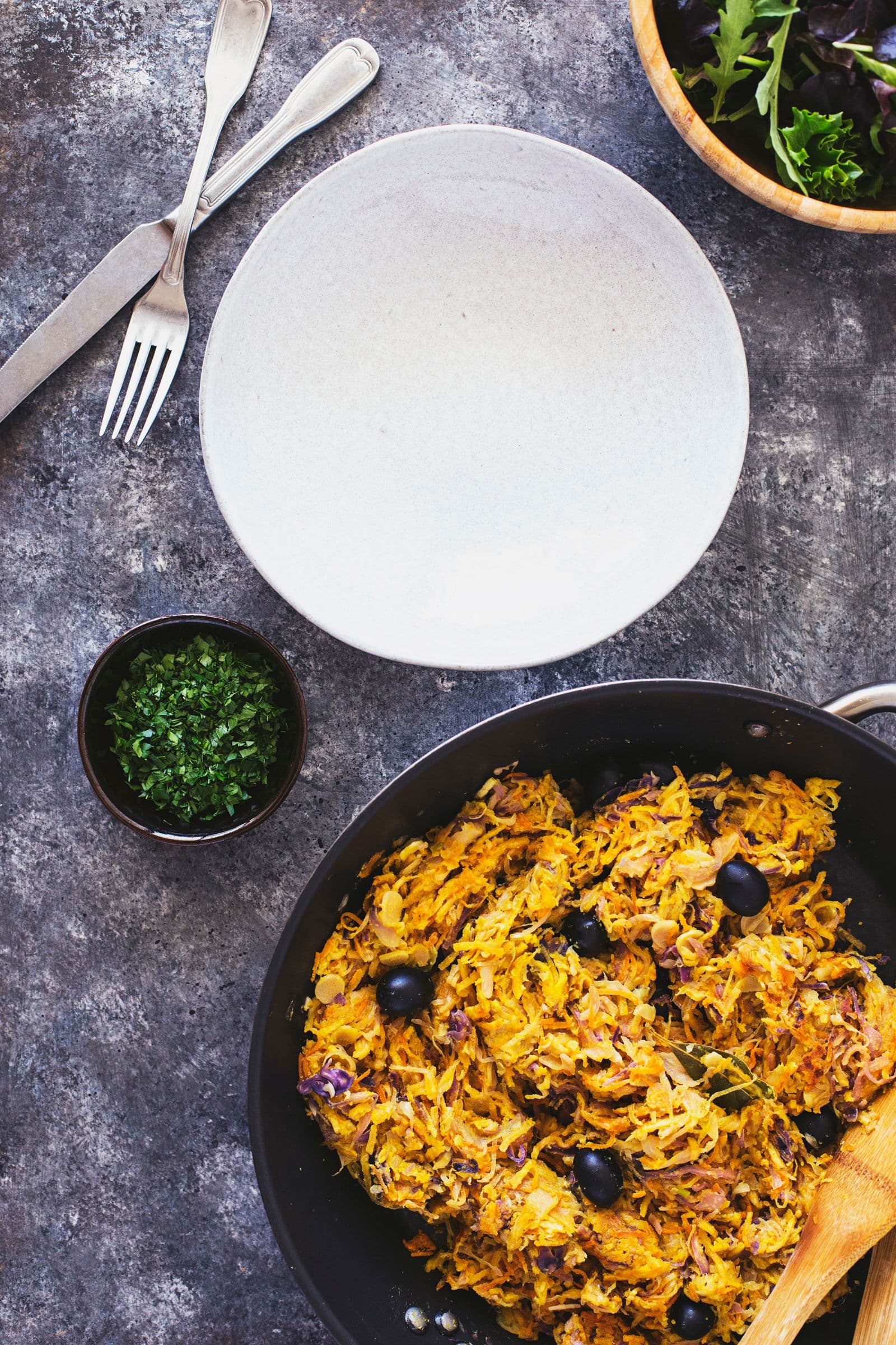 Portuguese veggie hash dotted with black olives, ready to serve.
