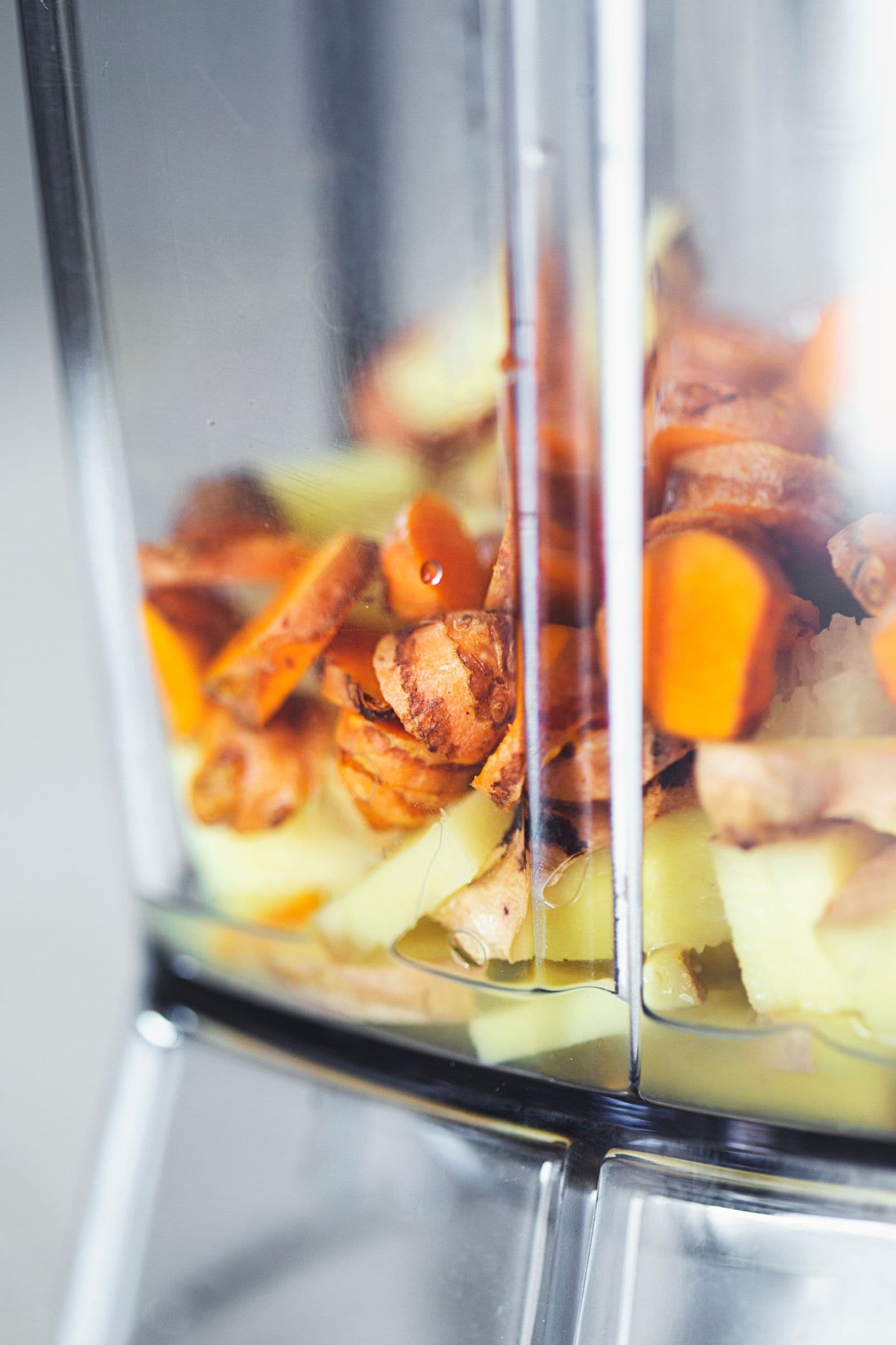 Copo de liquidificador com pedaços de gengibre, curcuma e sumo de limão.