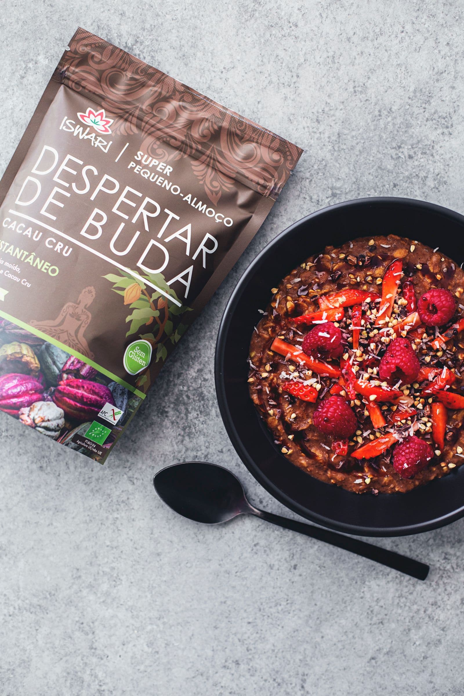 Bowl of cacao oatmeal served with raspberries and strawberries next to a packet of raw cacao breakfast mix.