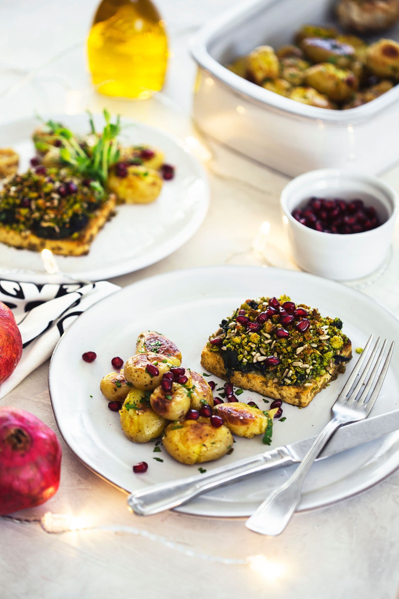 Christmas dinner table with tofu roast, roasted potatoes and festive lights.