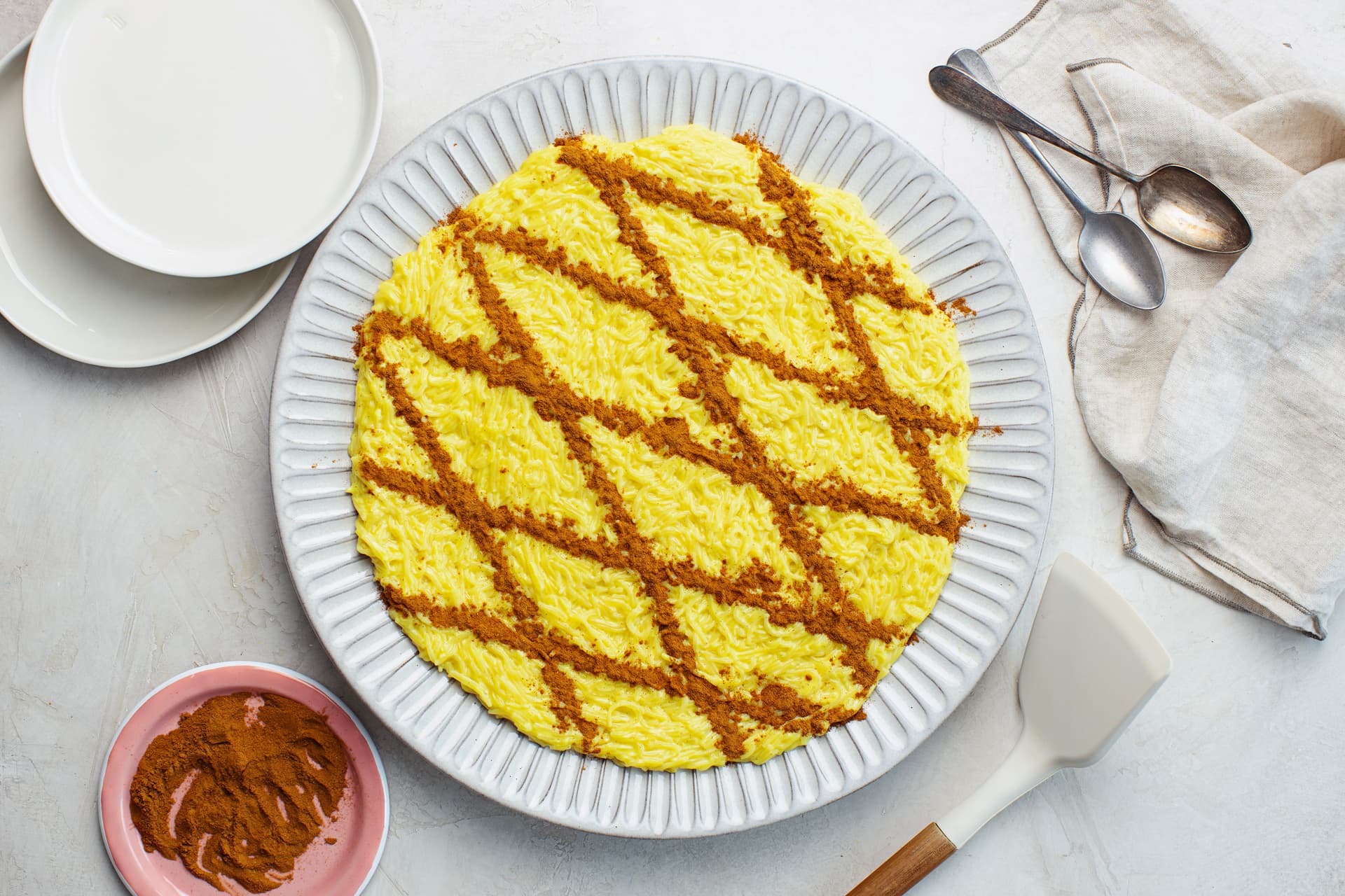 Overhead view of a large plate of vegan Aletria, a creamy Portuguese Christmas dessert topped with a cinnamon lattice pattern.