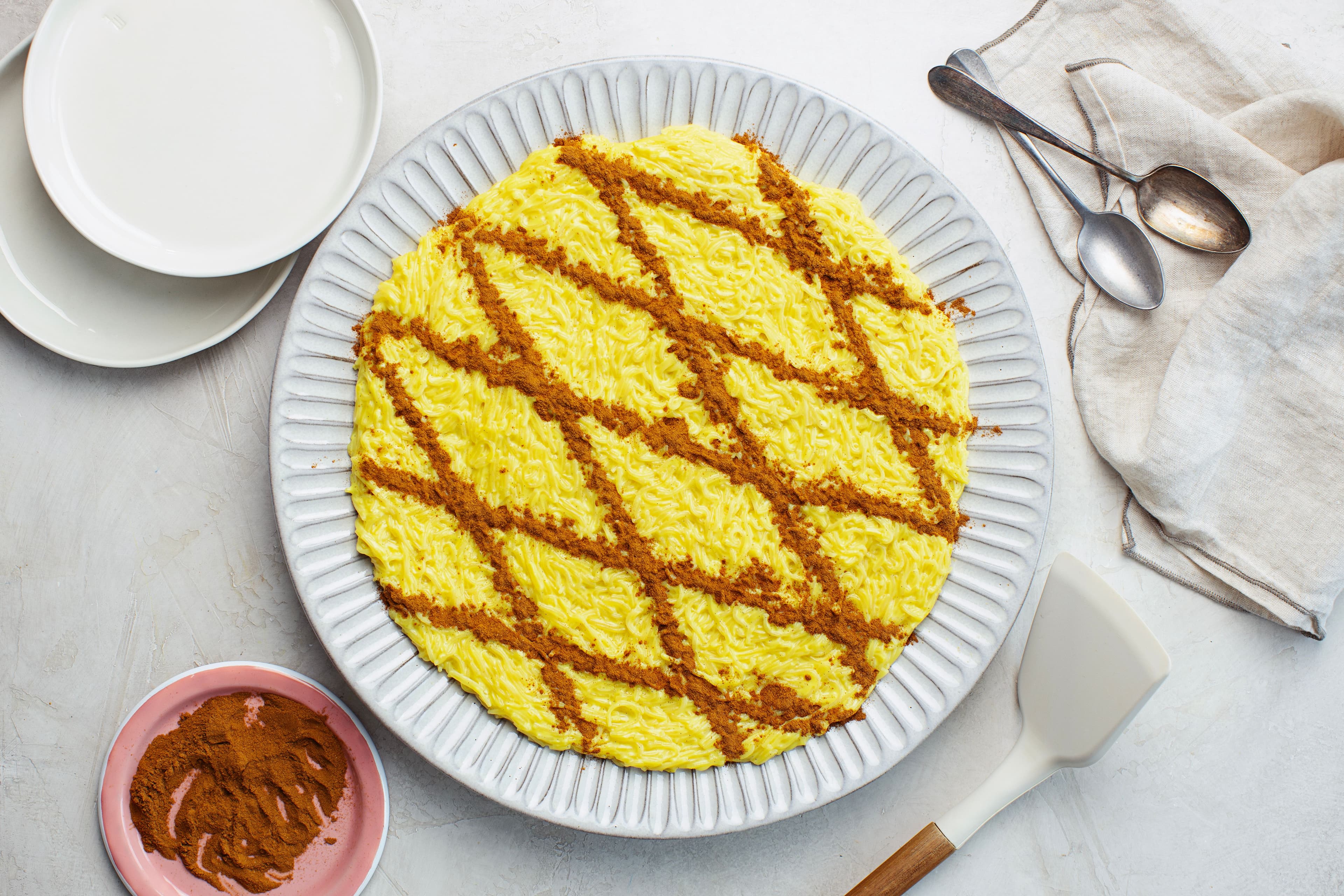 Overhead view of a large plate of vegan Aletria, a creamy Portuguese Christmas dessert topped with a cinnamon lattice pattern.