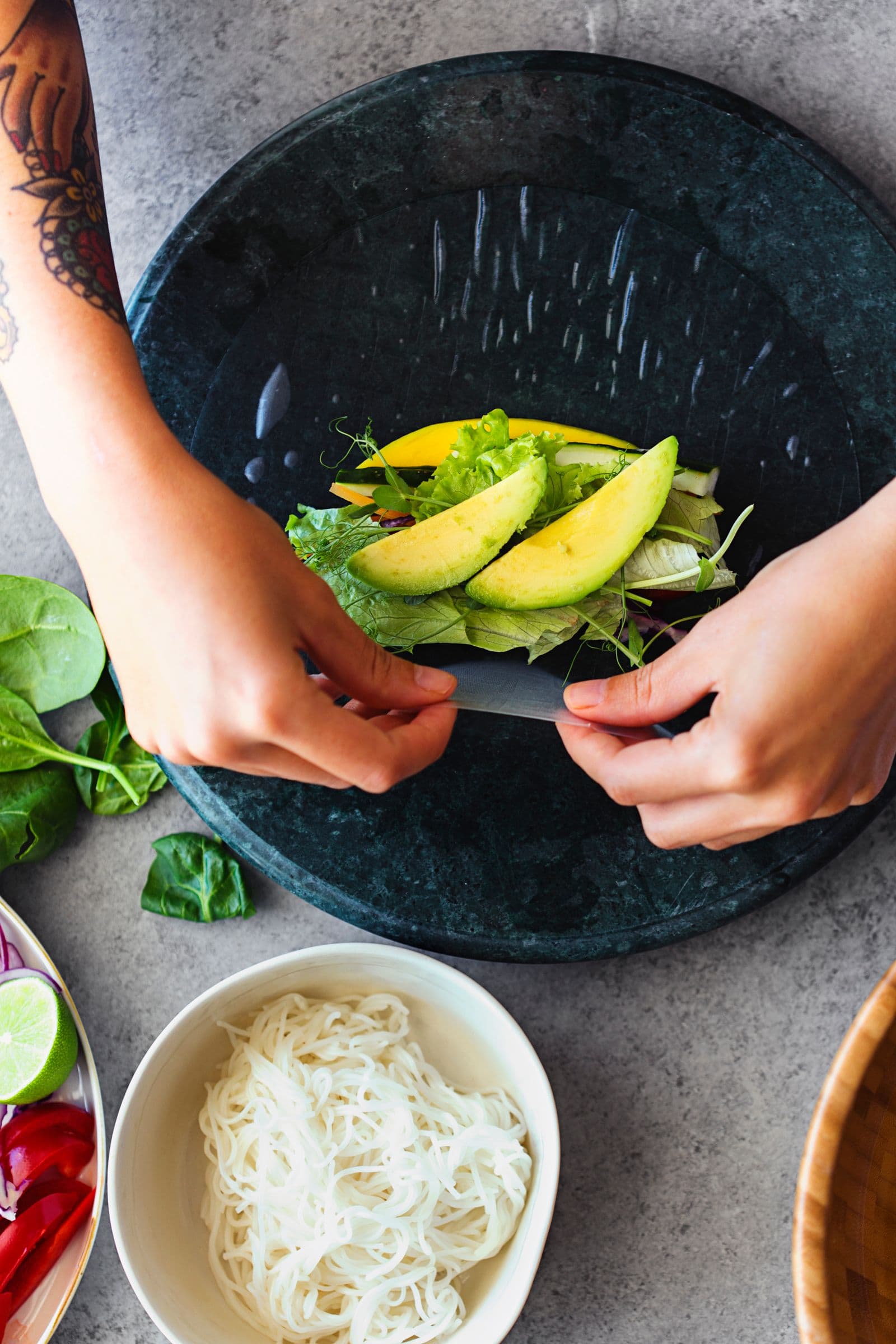 Preparing spring rolls with avocado slices and veggies.
