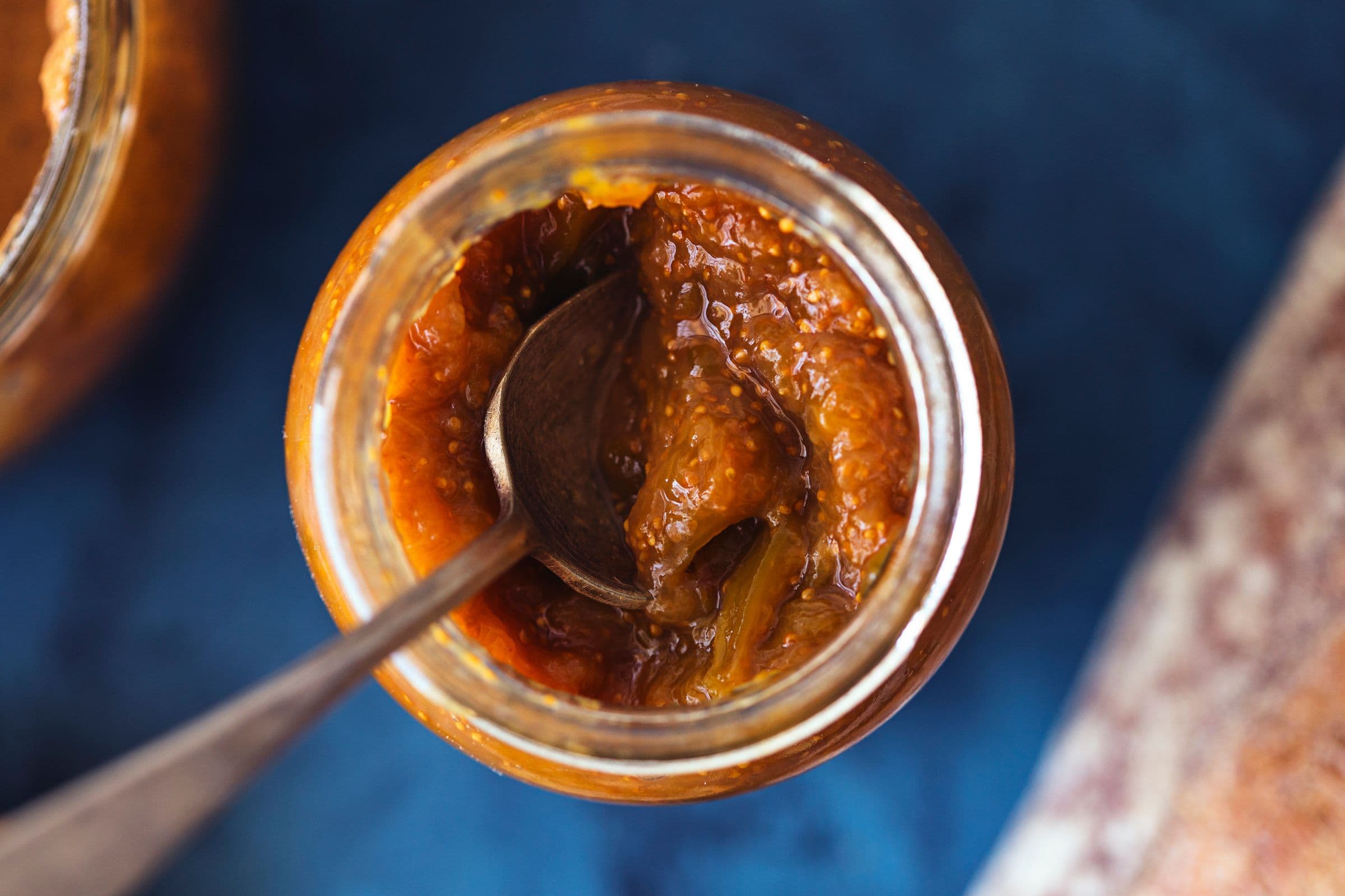 Close-up of a spoon dipped into thick fig and ginger jam.
