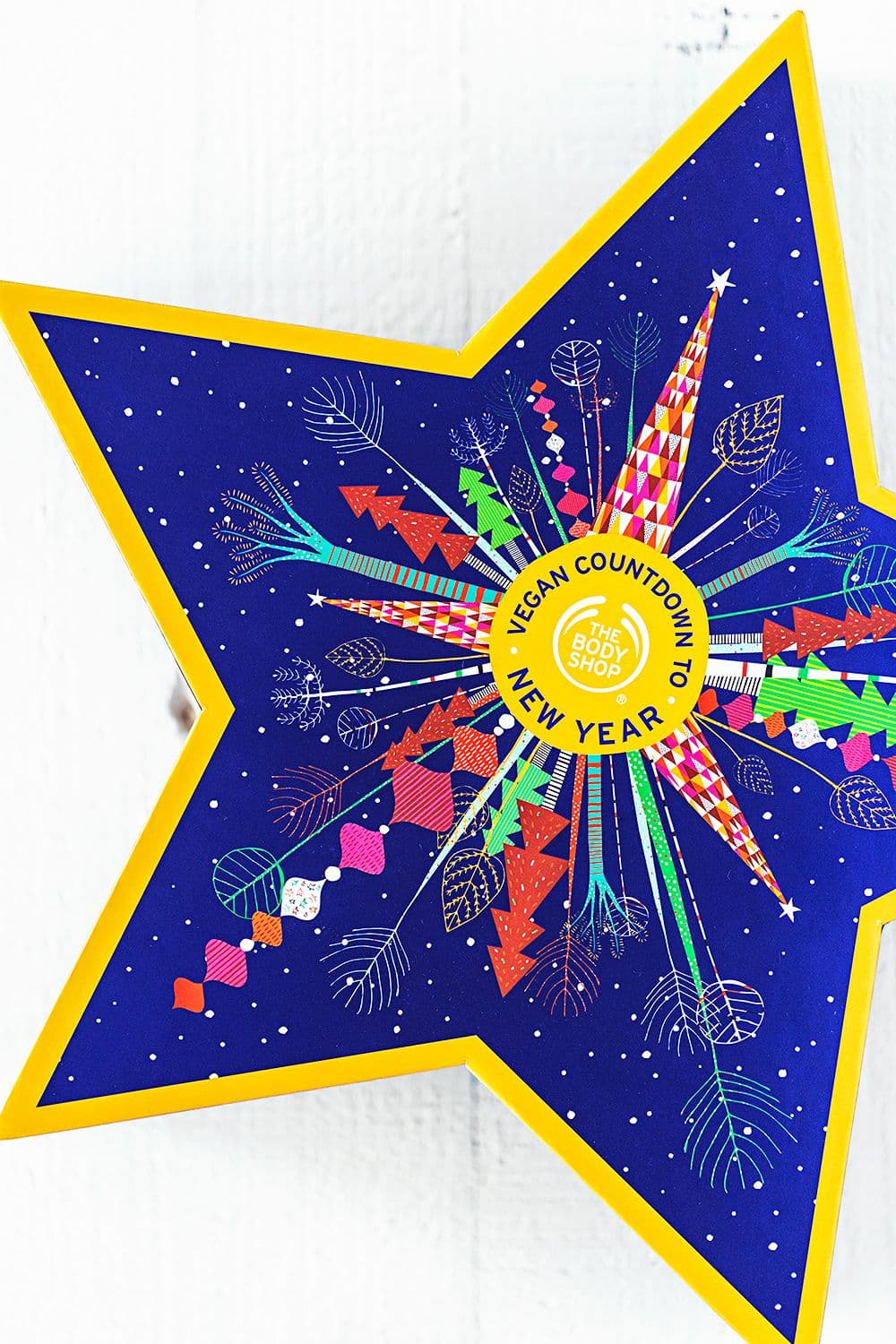 Star-shaped gift box with a blue background, colorful graphics, and “Vegan Countdown to New Year” by The Body Shop.