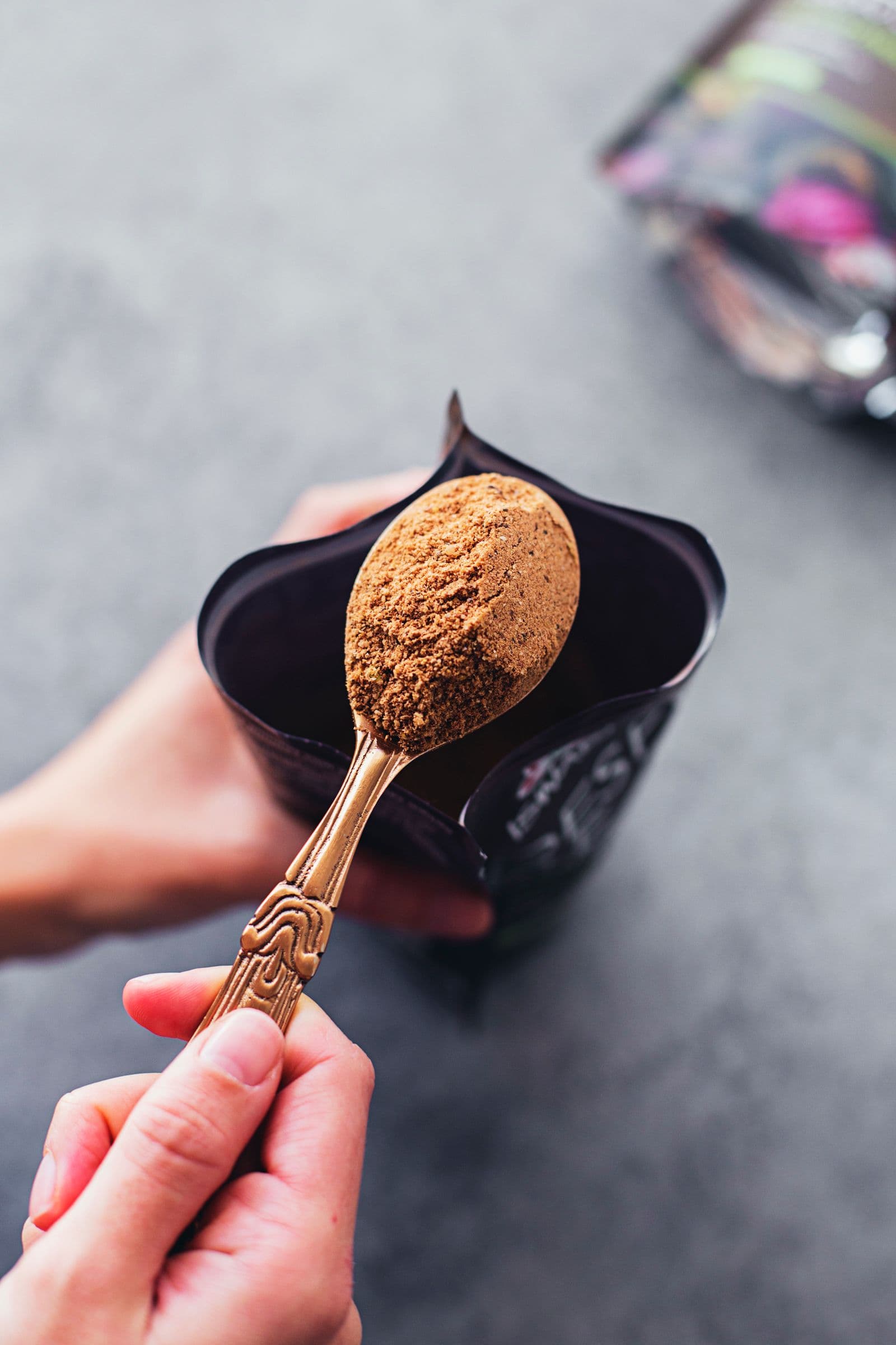 Hand holding a spoonful of the cacao mix over a bag.