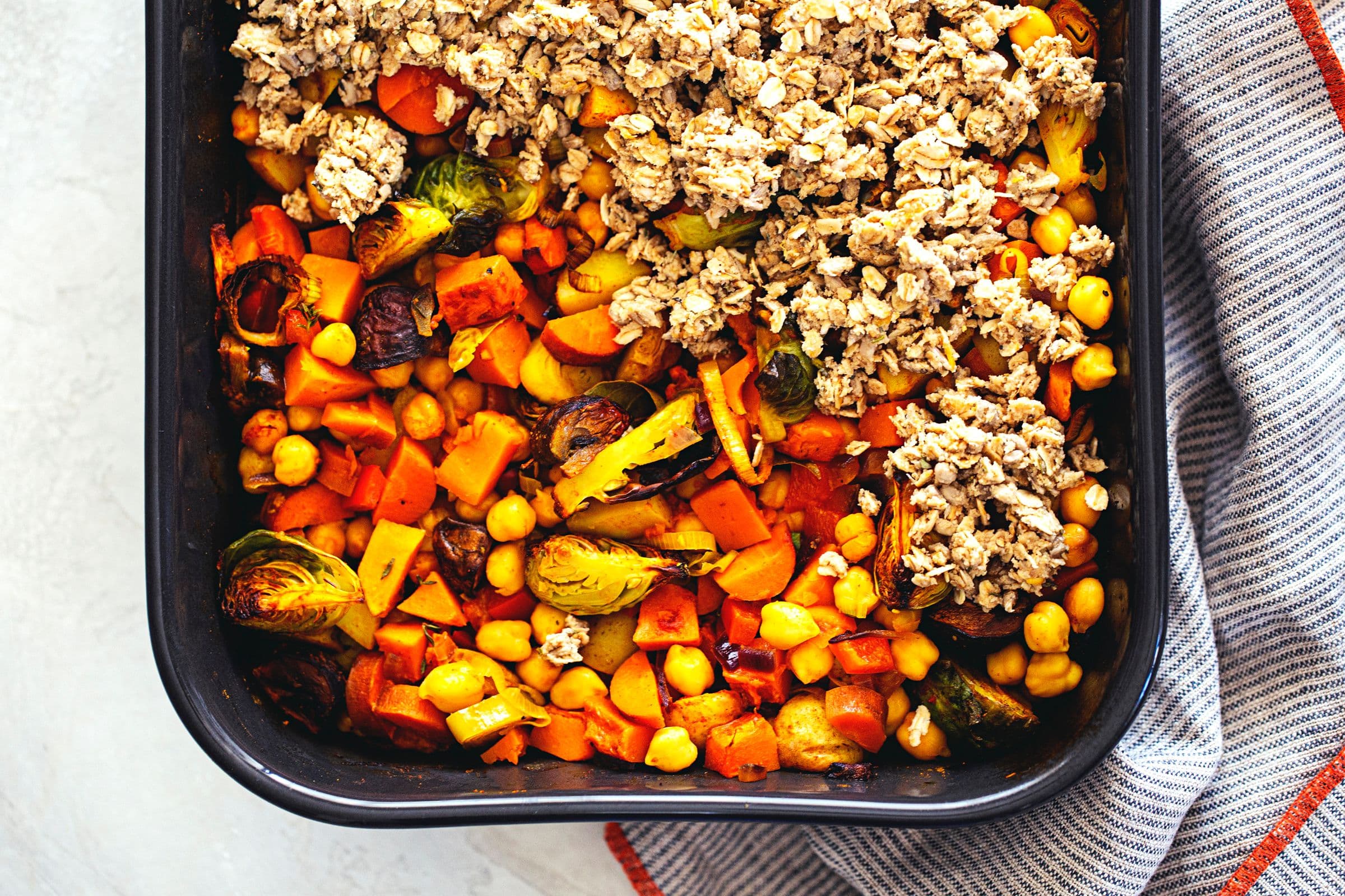 Baking dish with savoury veggie crumble, unbaked and ready for the oven.