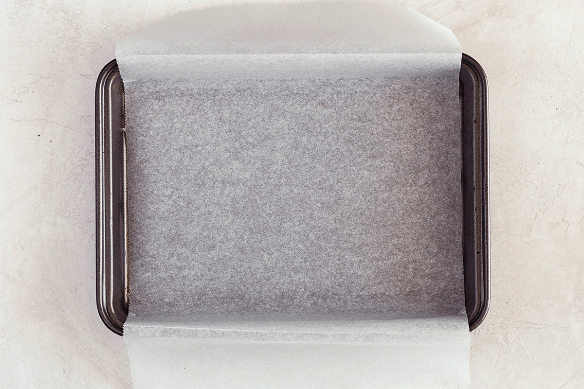 Animated gif of coffee flavoured coffee cake being assembled in a rectangular cake tin lined with parchment paper.