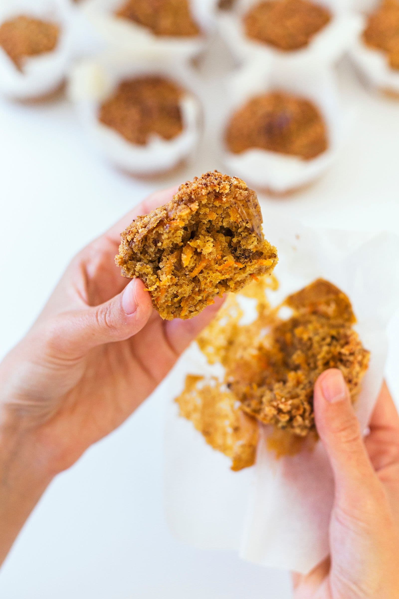 Hands breaking a muffin open, showing the fluffy interior.
