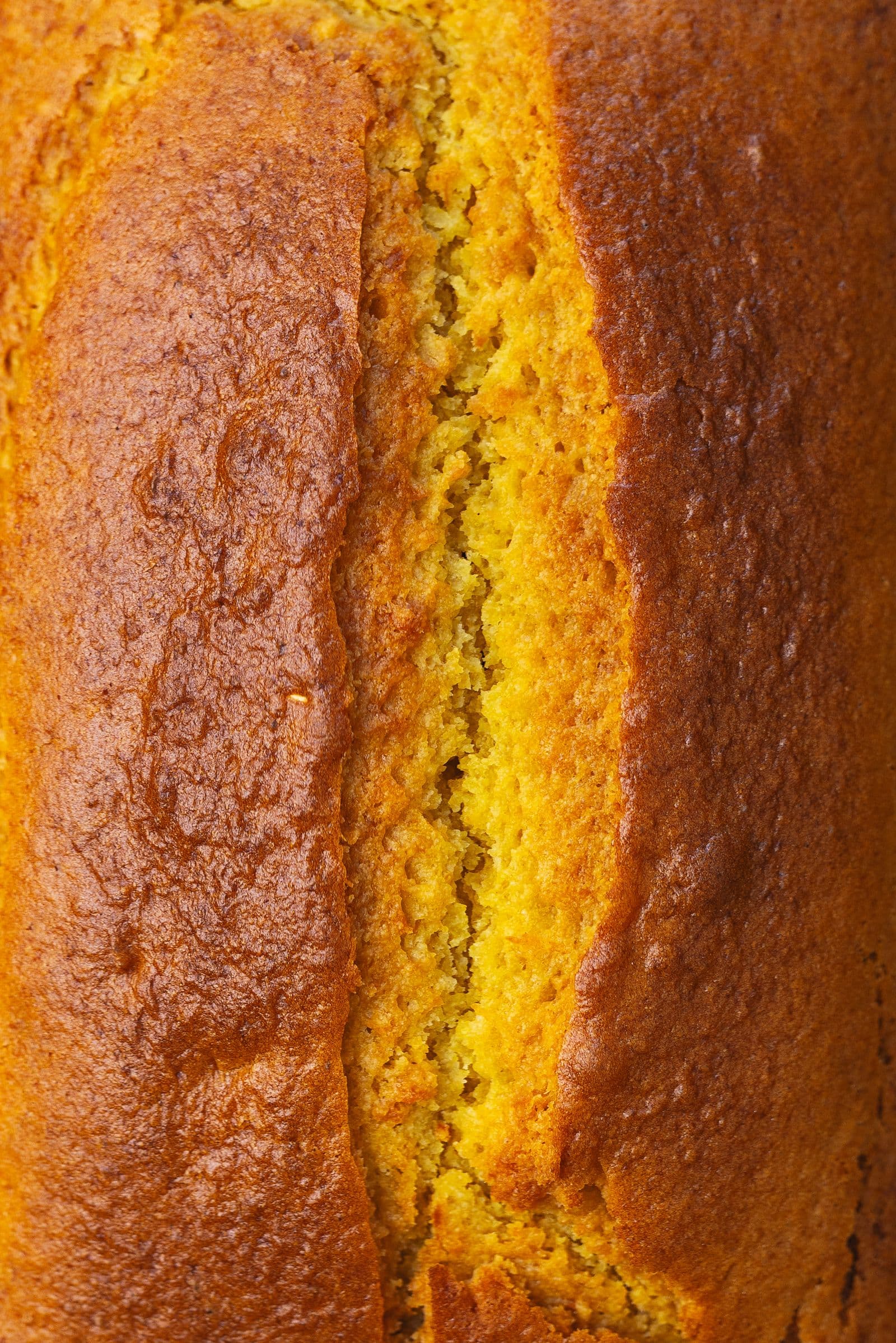 Detalhe da crosta dourada e fendida do bolo de laranja acabado de cozer.
