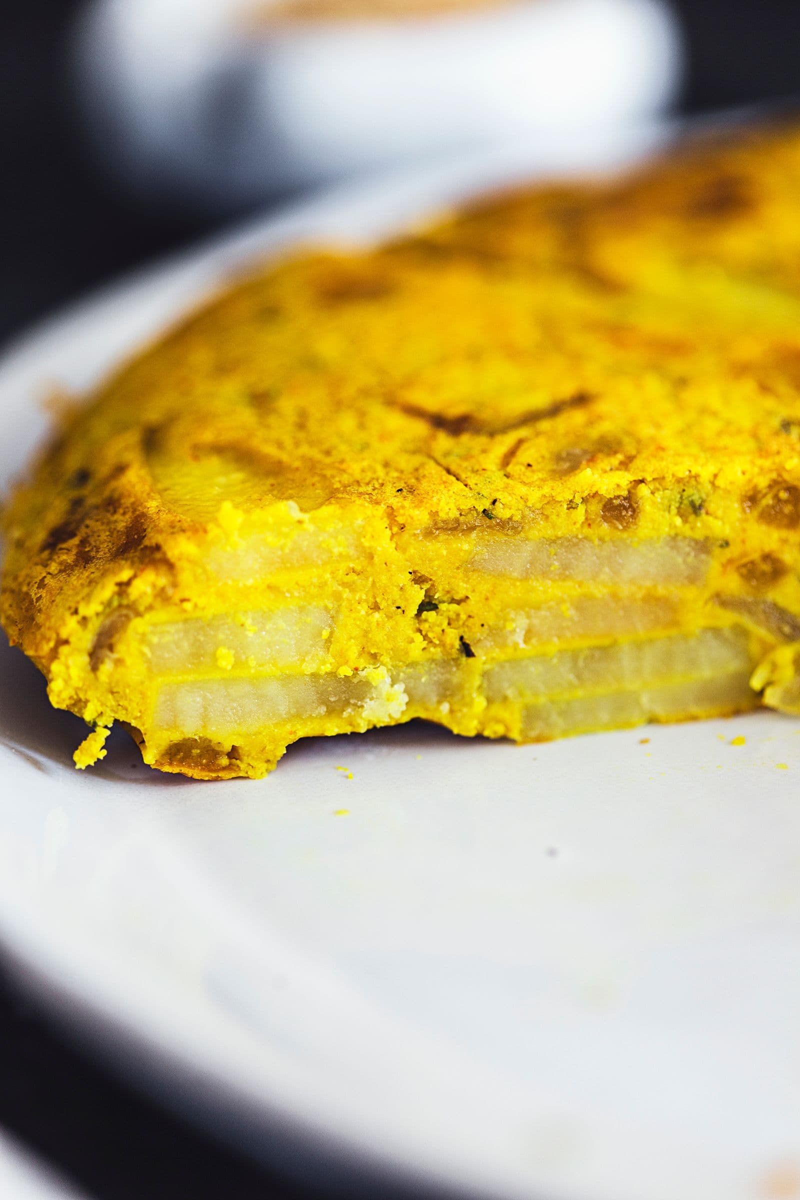 Fatia de tortilha num prato a mostrar as camadas de batata e cebola no interior.