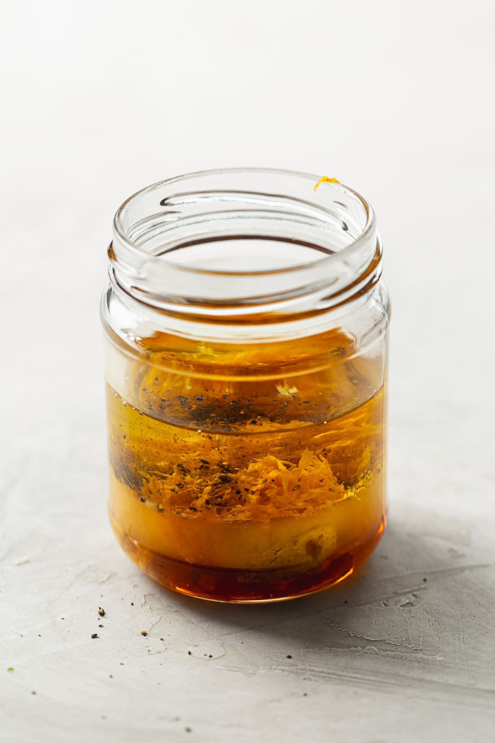 Orange, mustard and olive oil vinaigrette in a glass jar before shaking.