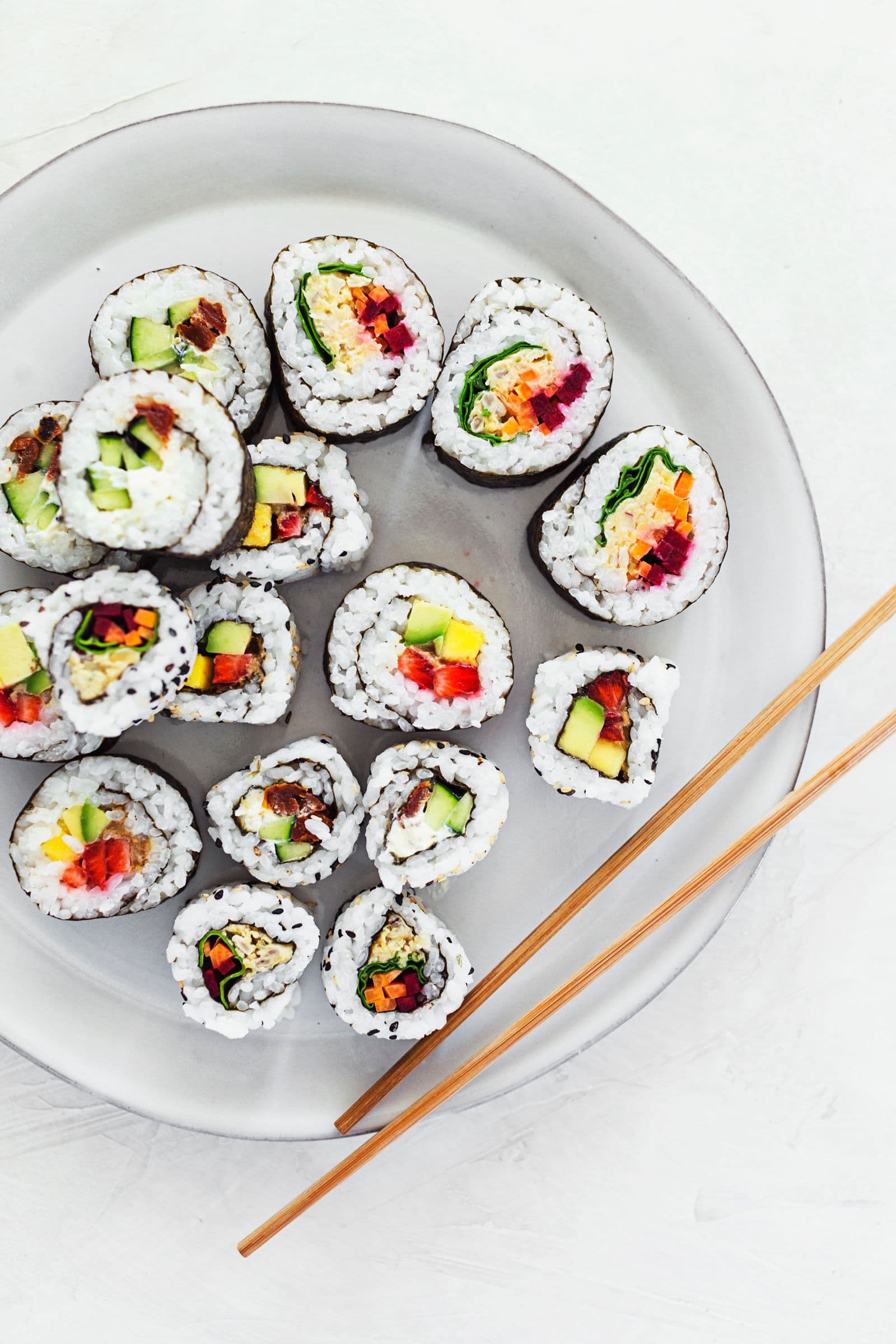 Rolinhos de sushi acabados de cortar servidos num prato com pauzinhos.