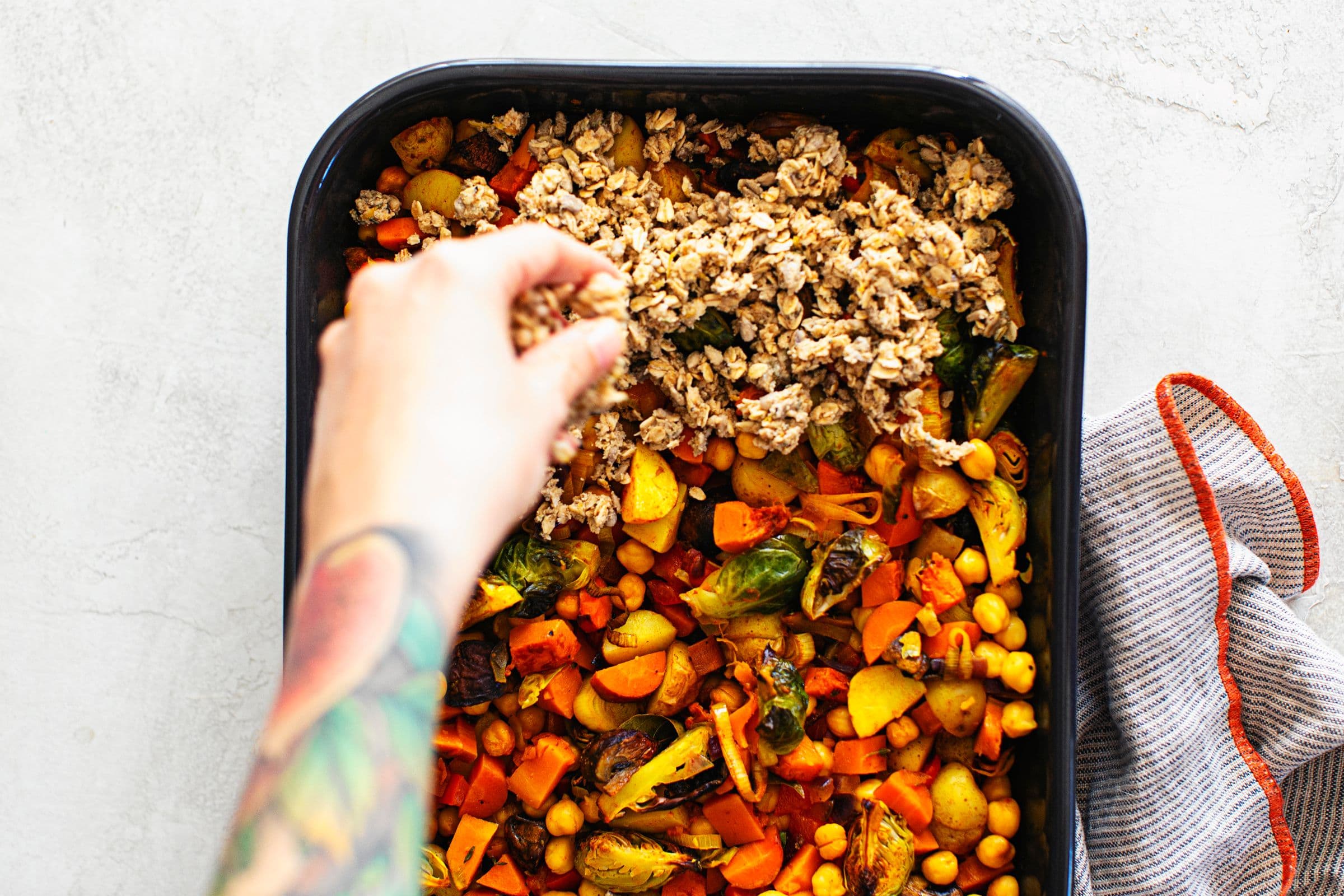 Assembling savoury vegan crumble, adding the crunchy topping layer.