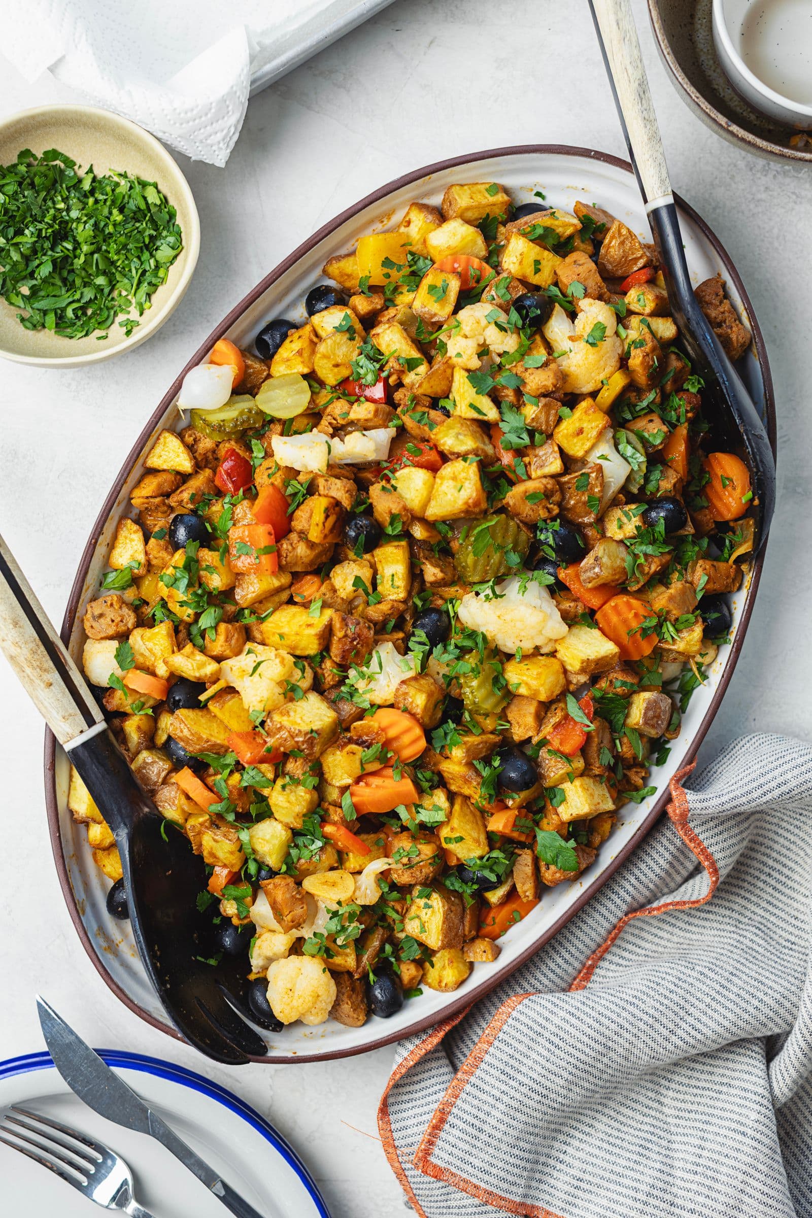 Vista aérea de travessa oval com pica pau de soja completo, polvilhado com salsa picada, com taça de salsa e talheres ao lado