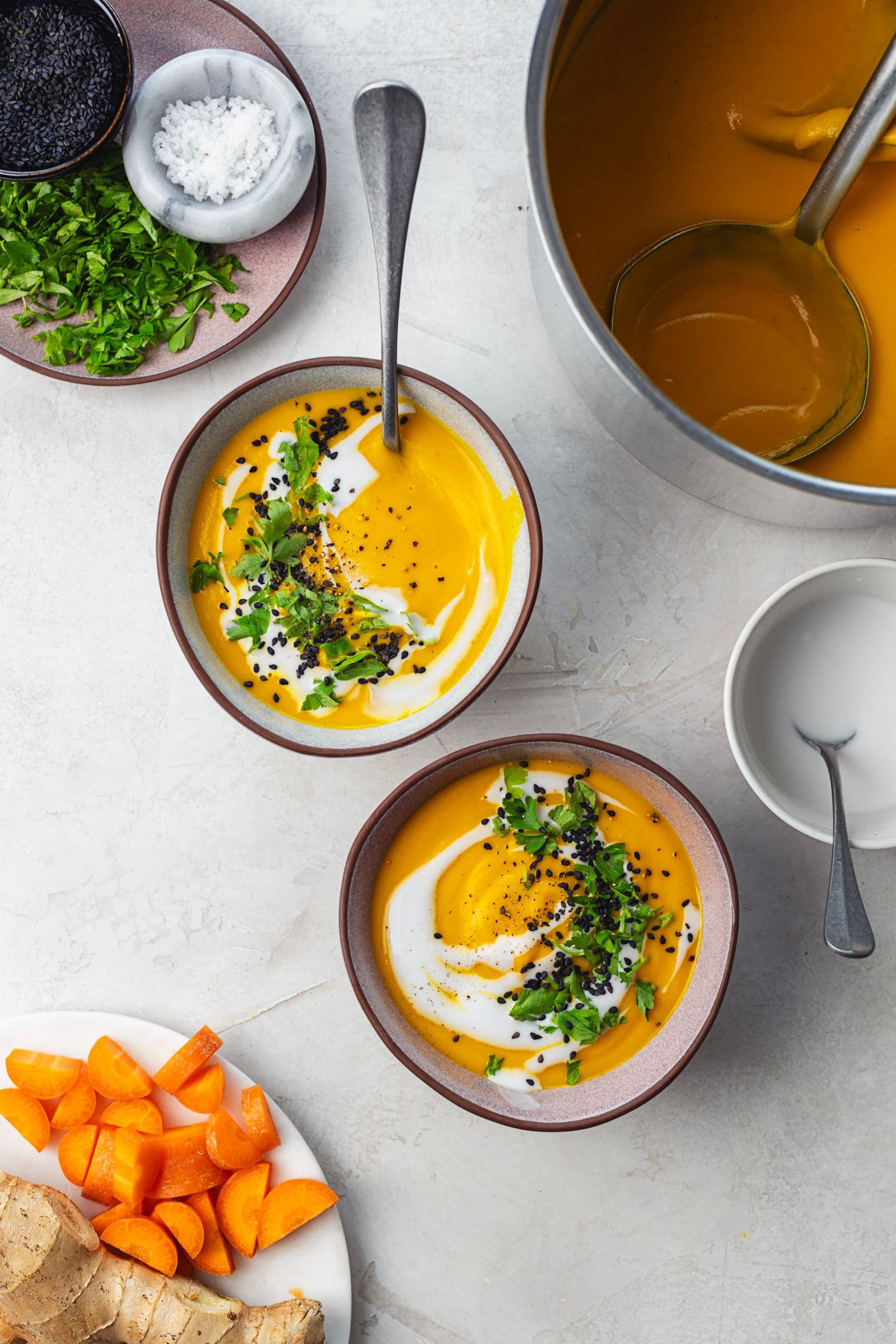 Warm bowl of soup with a spoon dipped in, showing the thick and creamy consistency of the carrot purée.