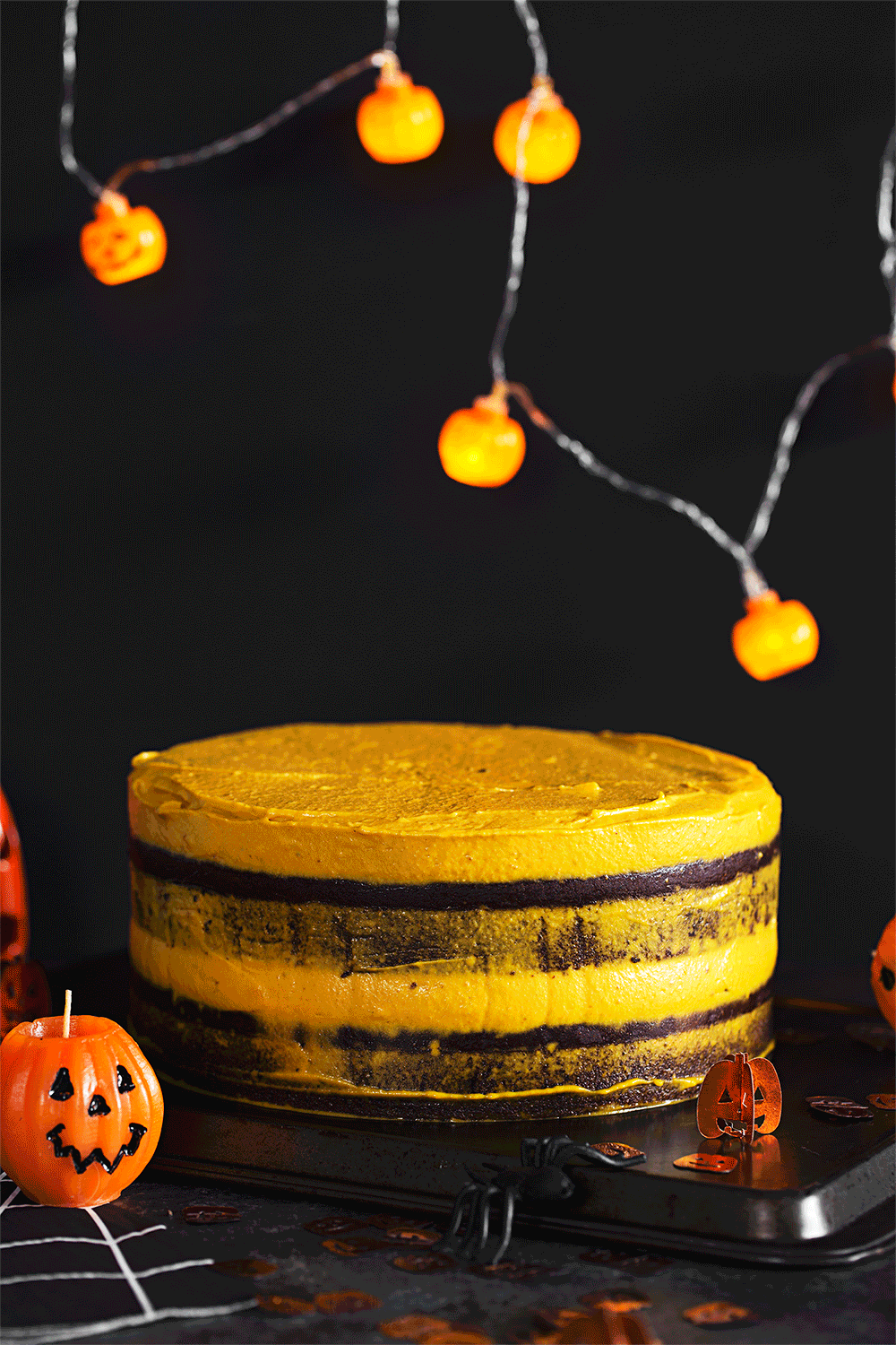 Animated gif of hand glazing Halloween-themed layered cake with glossy chocolate sauce.