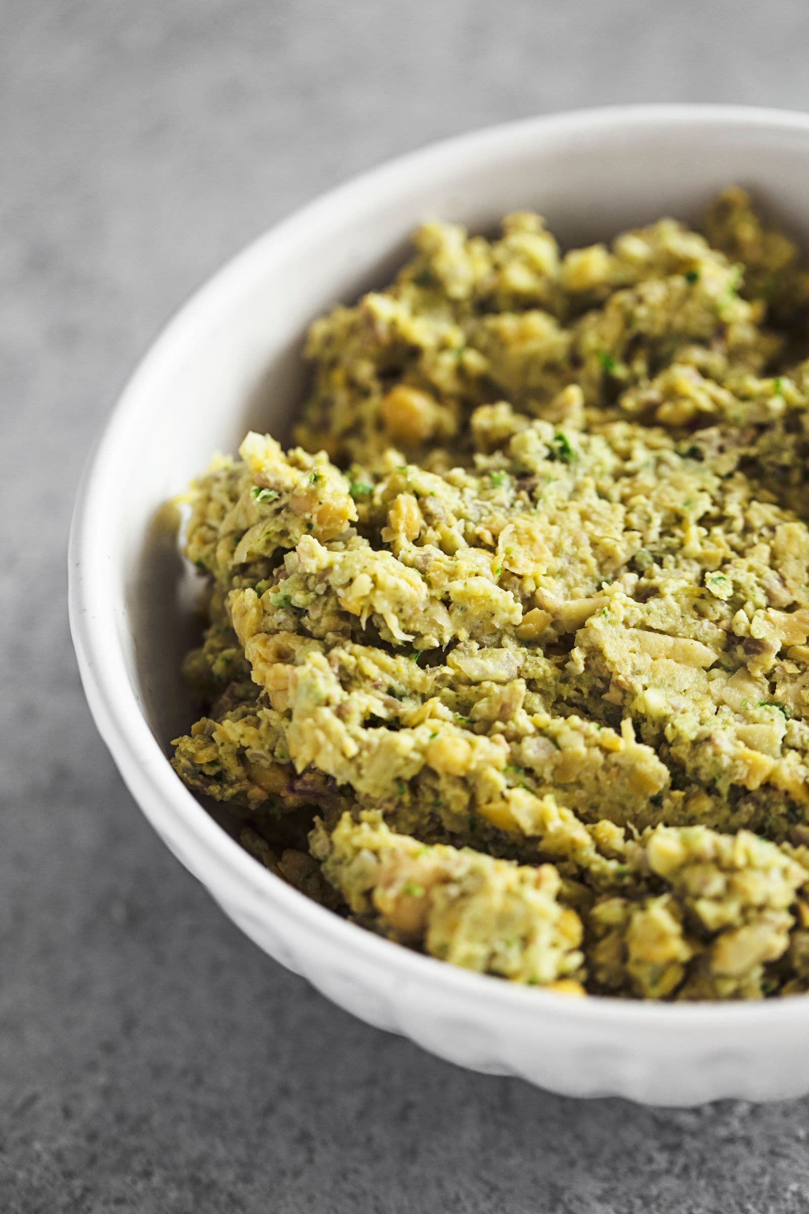 Pasta de grão e sementes de girassol servida numa taça branca.