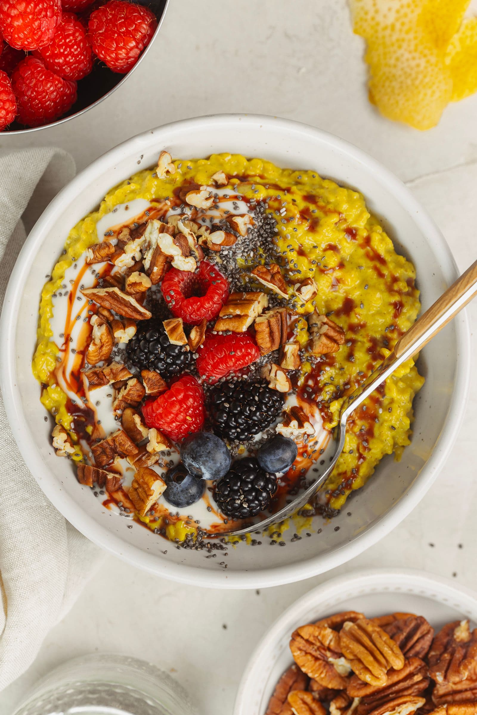 Papas de aveia com curcuma e toppings variados, como mirtilos, nozes pecã e chia, numa taça de pequeno-almoço rústica