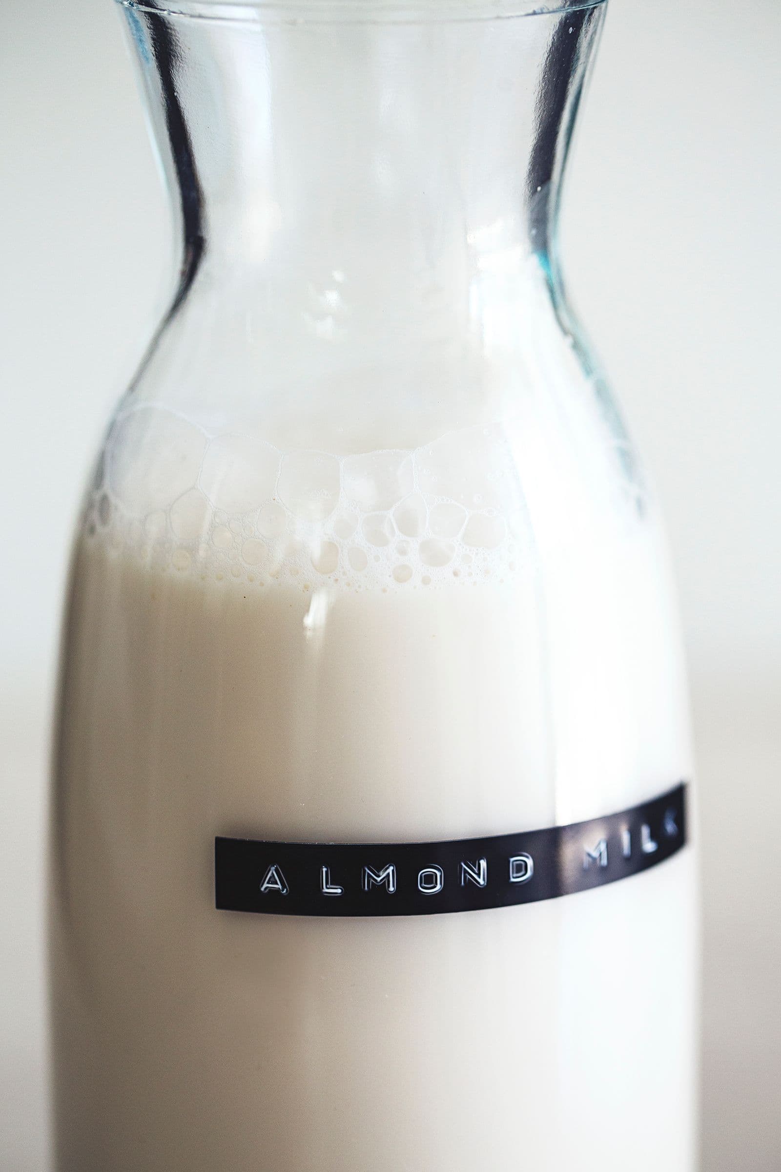 Garrafa de vidro com leite de amêndoa caseiro, com uma etiqueta preta a dizer "Almond Milk".