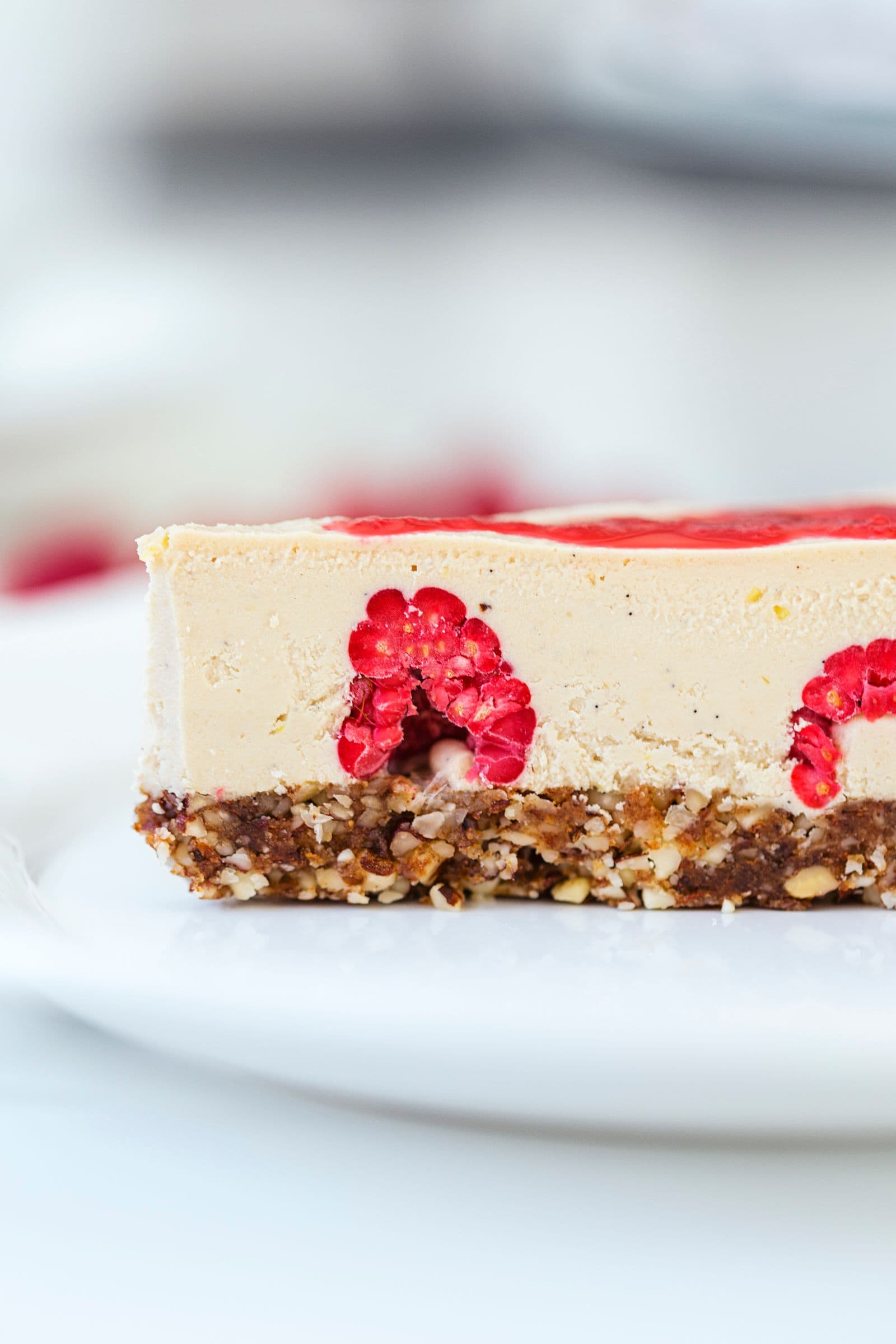 Close-up de uma fatia de cheesecake a mostrar o interior com framboesas.