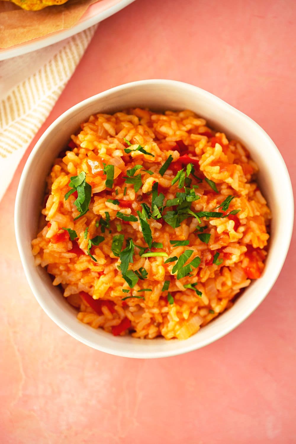 Tigela branca com arroz malandrinho de tomate e pimento, decorado com salsa fresca