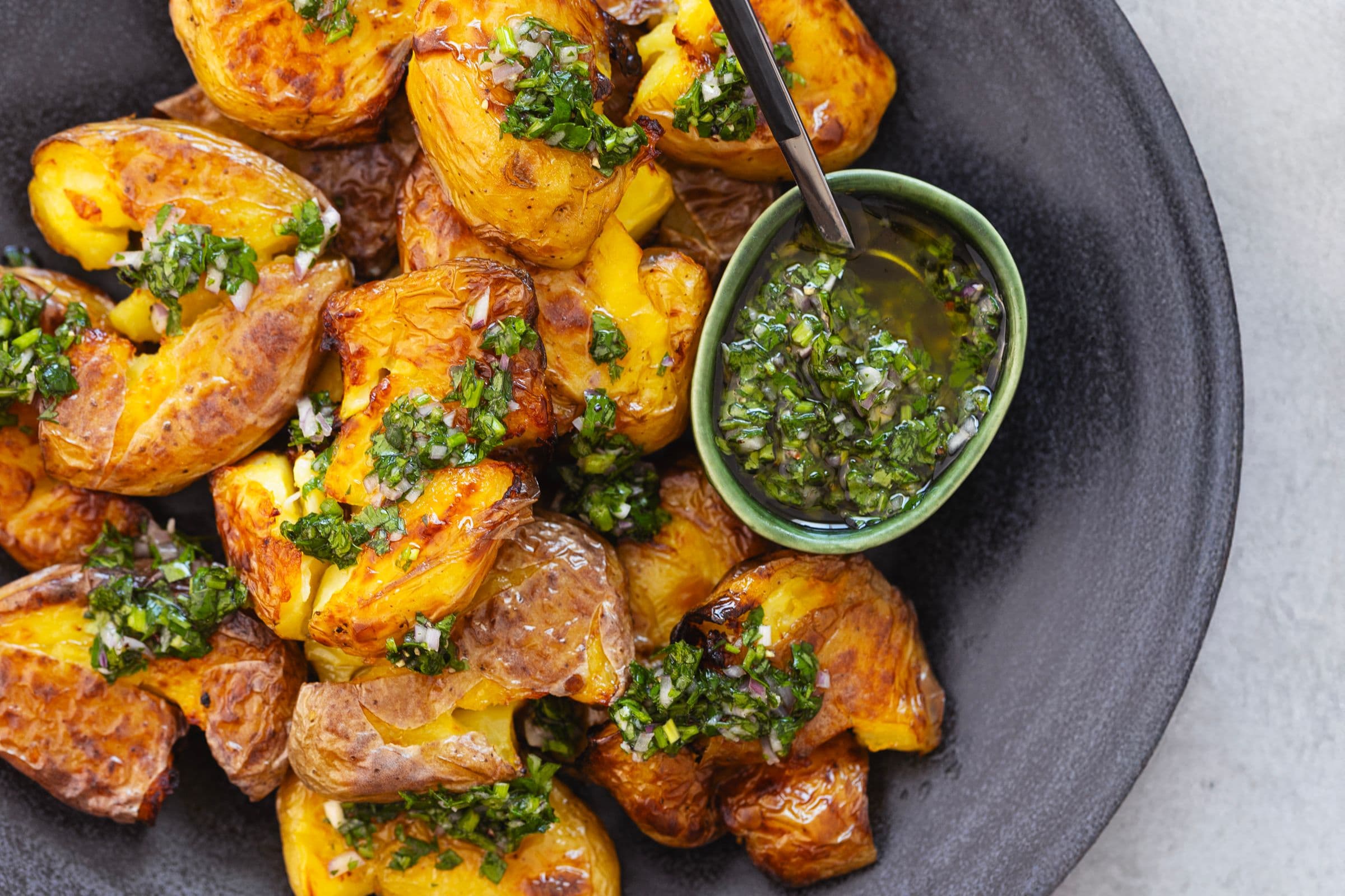 Batatas crocantes com ervas frescas, servidas com molho chimichurri em taça verde
