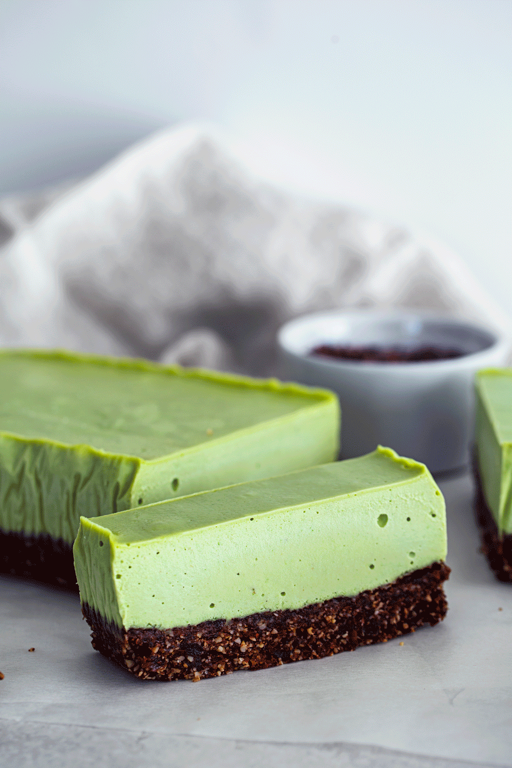 Gif animado de mão a verter chocolate derretido e a espalhar nibs de cacau sobre fatia de cheesecake de menta.