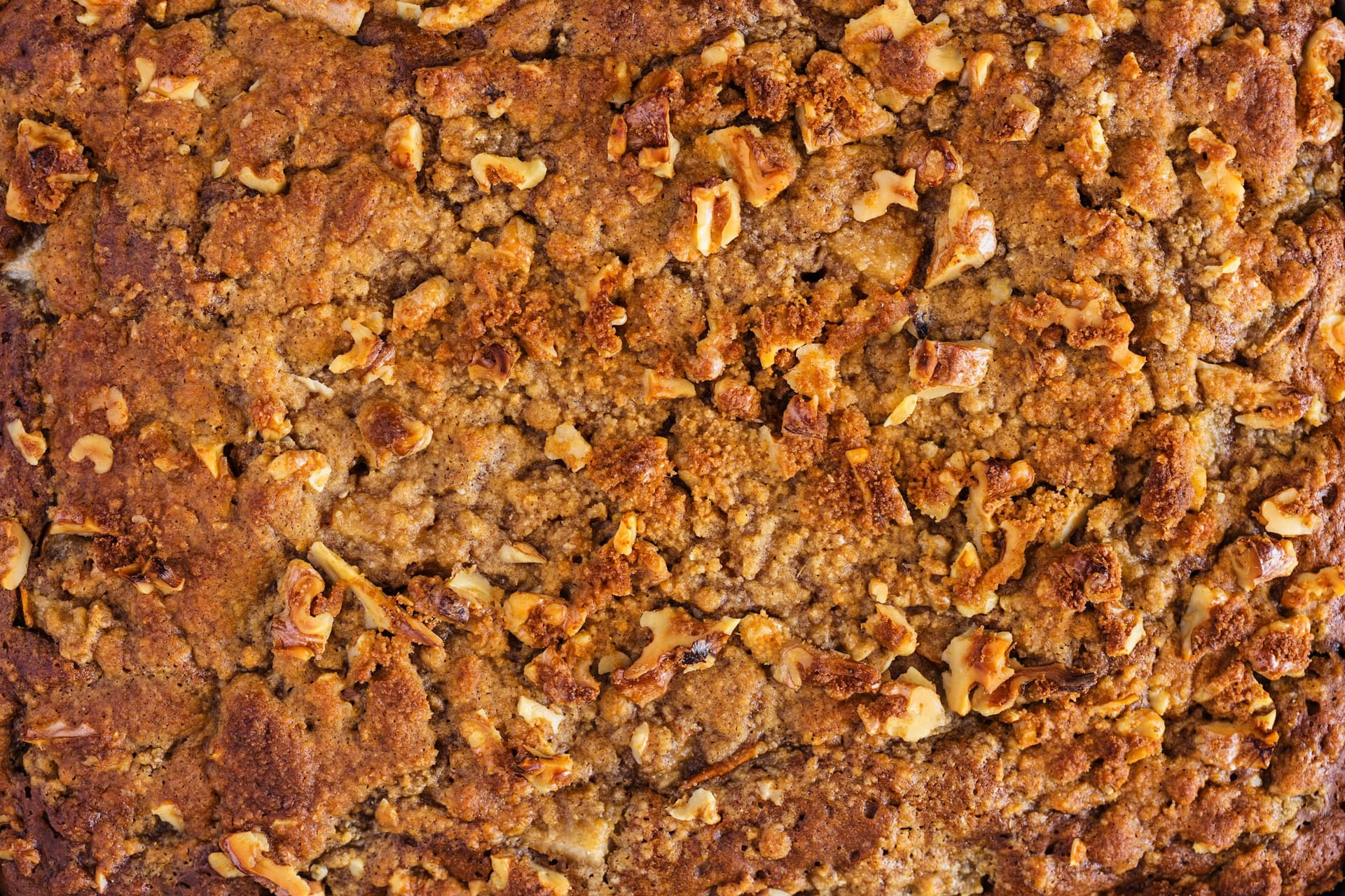 Bolo de café dourado com cobertura crocante de nozes, acabado de sair do forno.